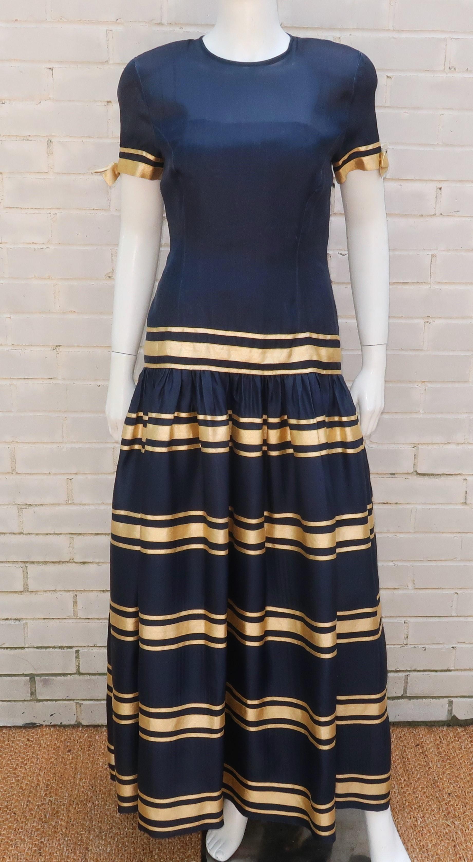 1980's Albert Nipon navy blue silk organza evening dress with bands of gold accented by bows.  The ultra feminine design zips and hooks at the back with a semi-transparent bodice lined with a camisole and shoulder line emphasized by pads ...