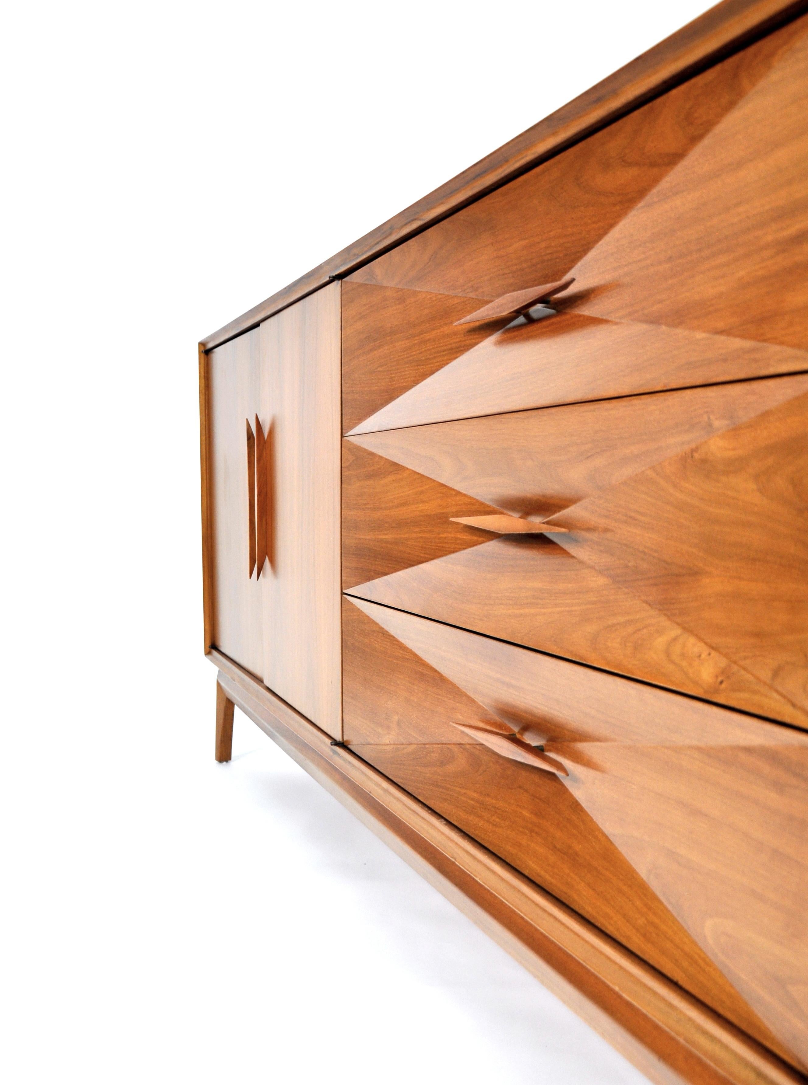 A superb Mid-Century Modern walnut credenza by Albert Parvin. Freshly restored and ready for your home or office, the sculptural dresser provides ample storage space. The drawer fronts have a striking concave diamond Front Design and signature