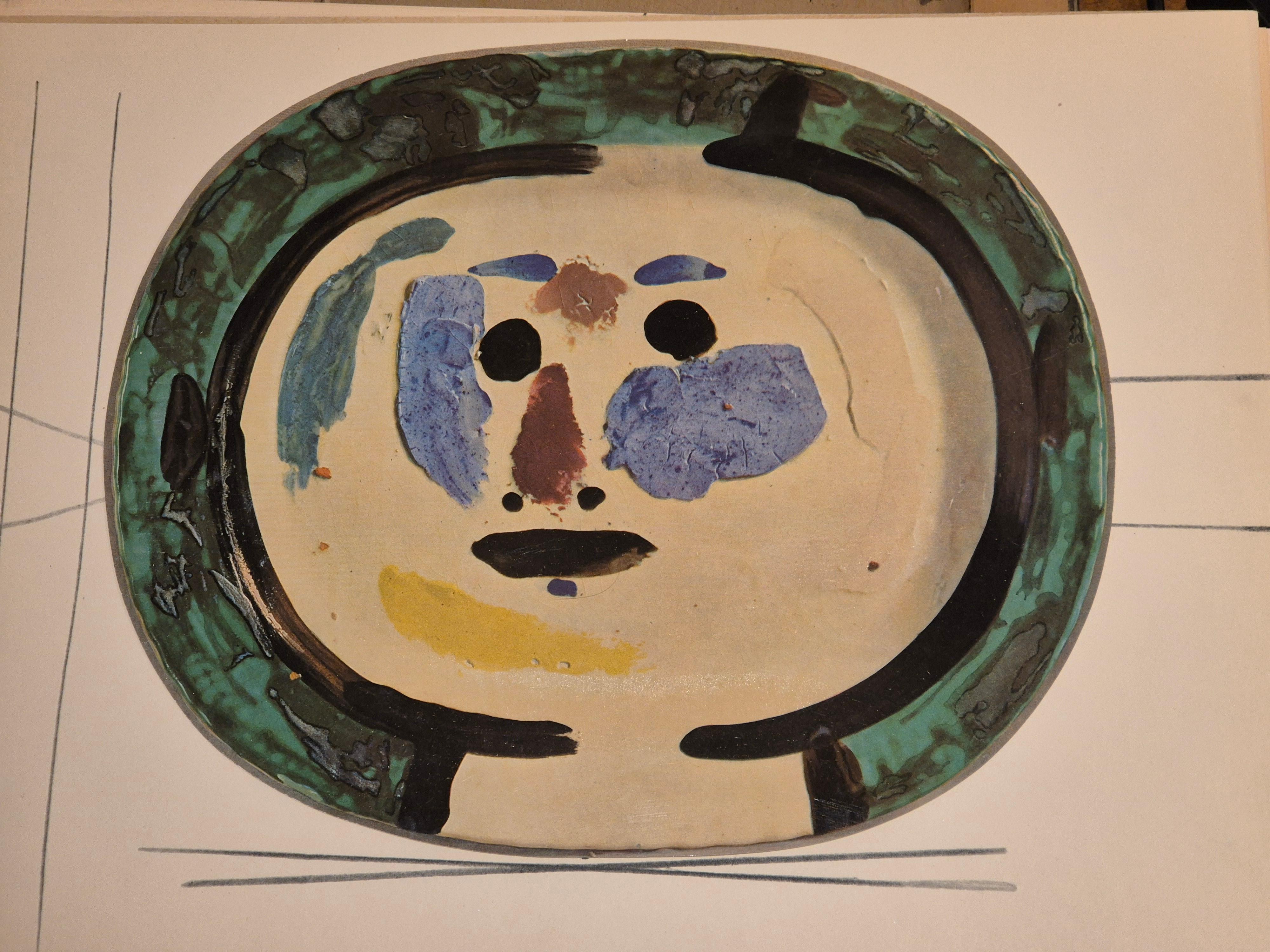 Une exquise impression polychrome brillante de l'assiette en céramique de Picasso Vallauris représentant un visage. L'impression en couleur est fixée sur un papier épais de haute qualité avec des lignes décoratives. 

L'estampe provient d'une