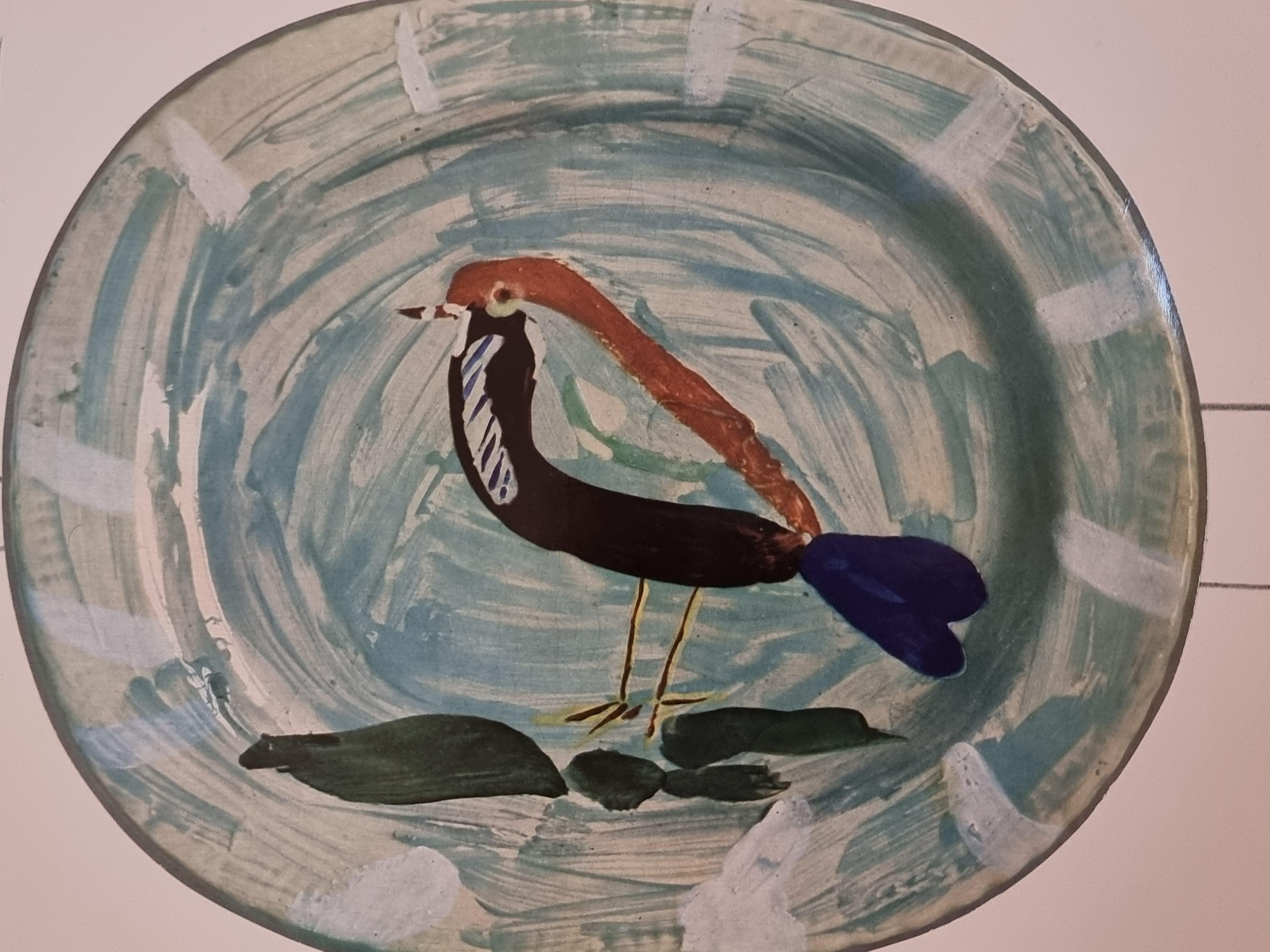 An exquisite shiny polychrome print of Picasso Vallauris ceramic plate depicting a bird. The color print is attached to a thick, high quality paper with decorative lines. 

The print is originally from a Limited Edition Art Folio 