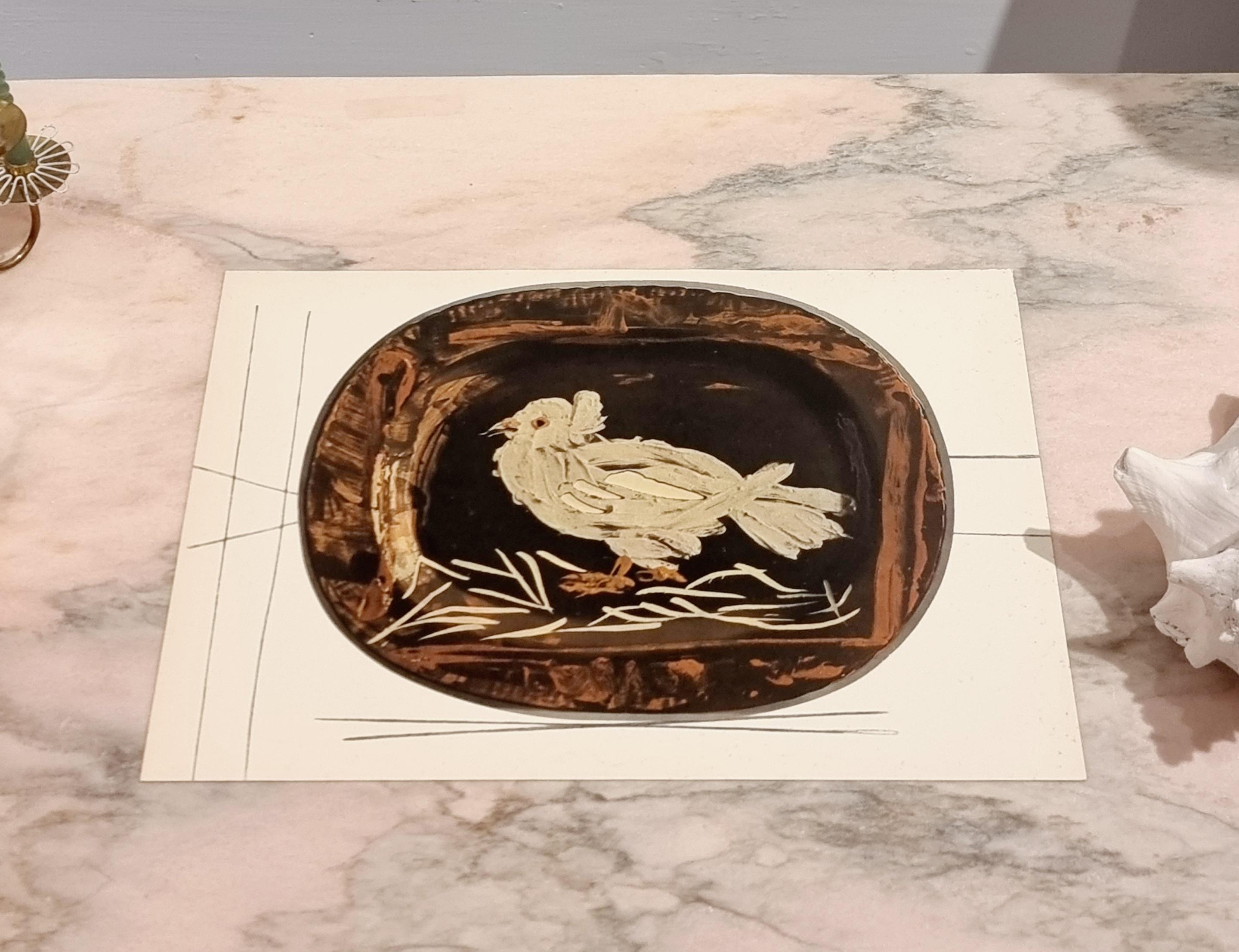An exquisite shiny polychrome print of Picasso Vallauris ceramic plate depicting a bird. The color print is attached to a thick, high quality paper with decorative lines. 

The print is originally from a Limited Edition Art Folio 