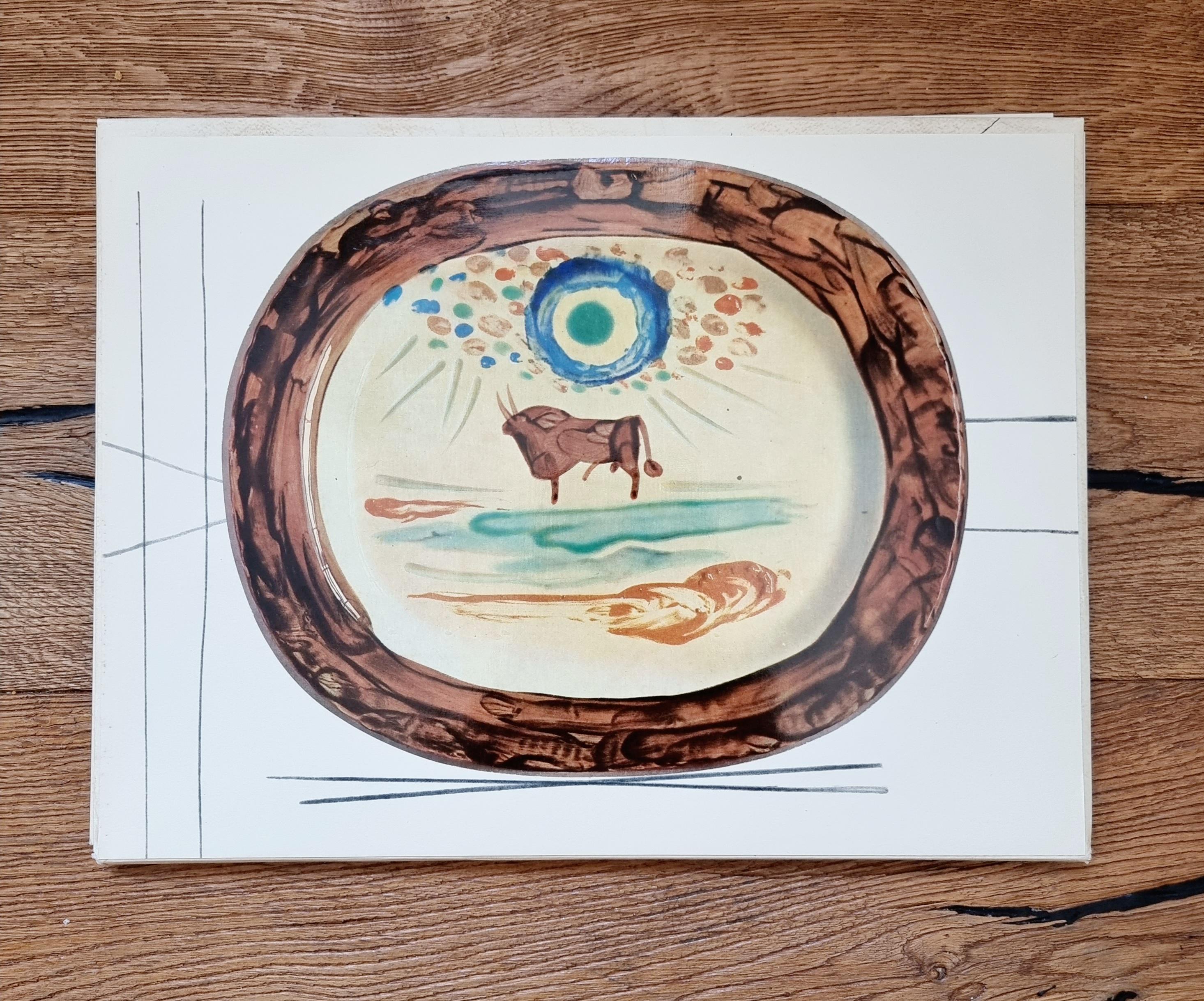 An exquisite shiny polychrome print of Picasso Vallauris ceramic plate depicting a bull on a field. The color print is attached to a thick, high quality paper with decorative lines. 

The print is originally from a Limited Edition Art Folio