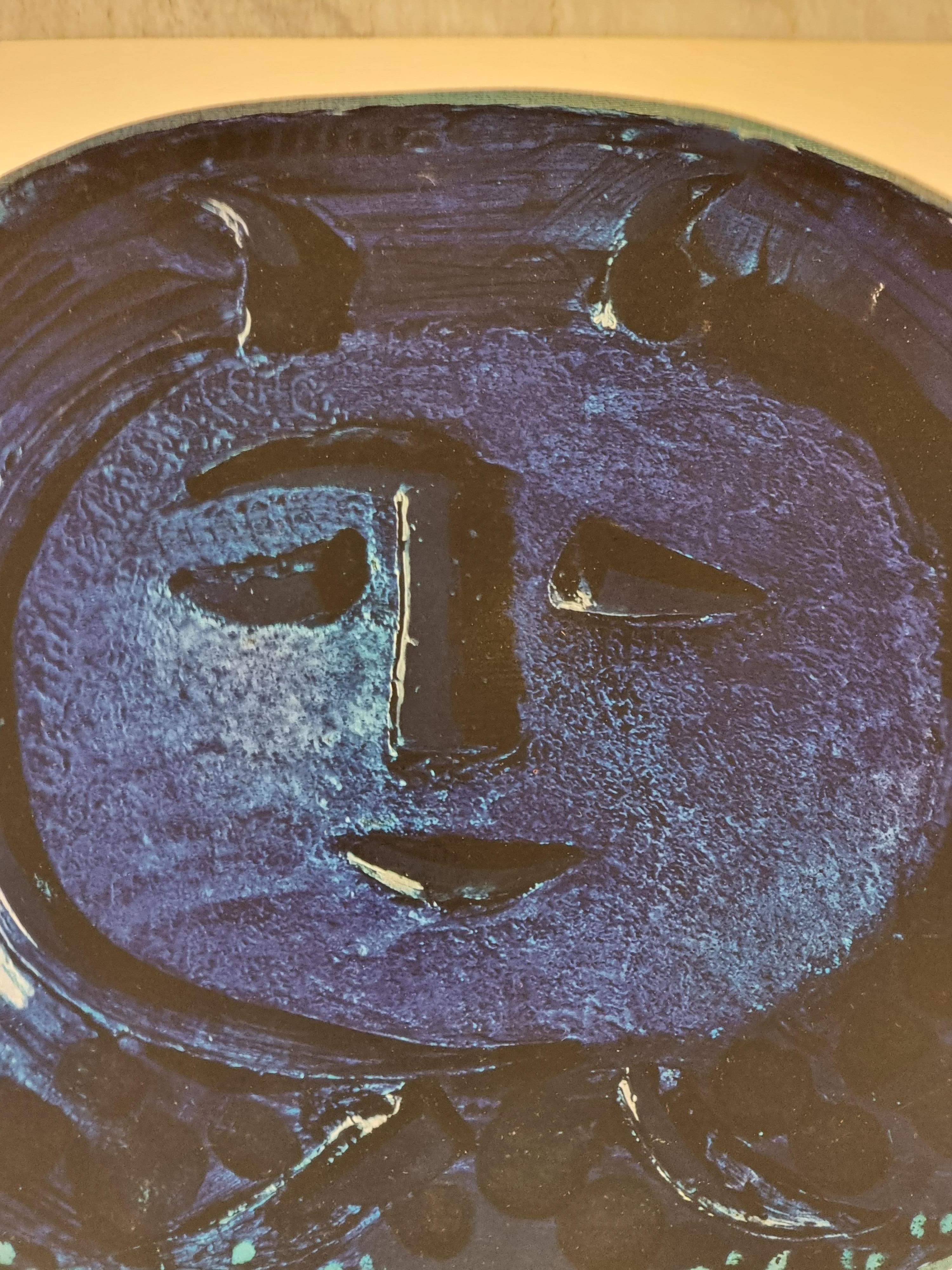 An exquisite shiny polychrome print of Picasso Vallauris ceramic plate depicting face in blue. The color print is attached to a thick, high quality paper with decorative lines. 

The print is originally from a Limited Edition Art Folio 