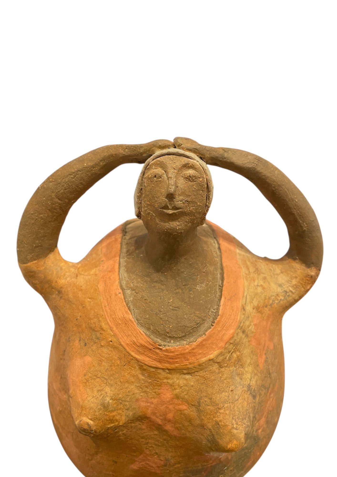 Figura in terracotta policroma raffigurante una donna con le braccia sollevate appoggiate sulla testa. Il corpo arrotondato è decorato con motivi di stelle rosso-arancio e la base poggia su un piccolo basamento rettangolare. Un'opera moderna nello