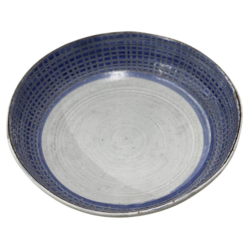 The ceramic's blue and white tones are both elegant and vibrant. 
The blue lines strewn around the ring are typical of mid-century embellishments. This huge Thiry dish is decorated with intaglio engraving. 
This plate was created by Albert Thiry,