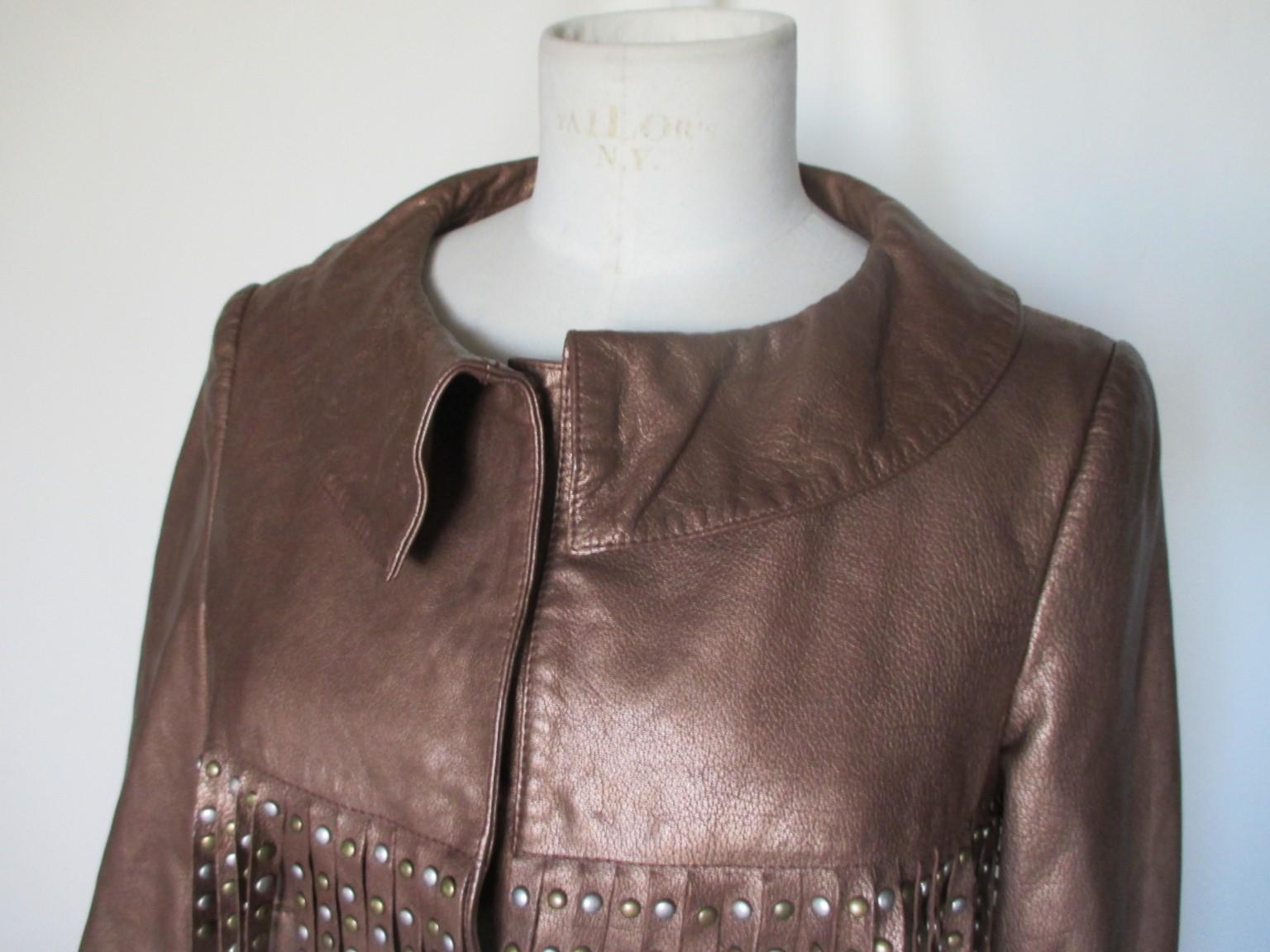 This is a leather fringe jacket from Alberta Ferretti.

We offer more exclusive vintage items, view our frontstore.

Details:
Made of metallic bronze leather, with gold and silver studs on fringe
With 7 press buttons, no pockets
3/4 sleeves
Fully