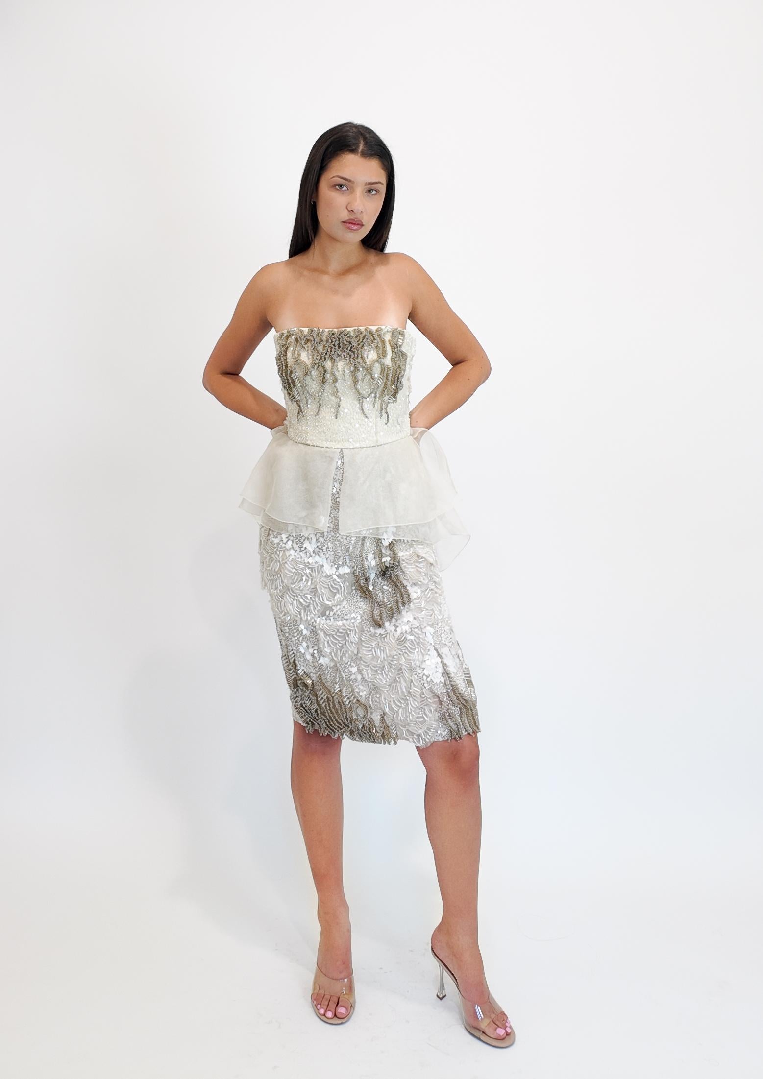 Este vestido de cóctel Alberta Ferretti S/S 2013 está extravagantemente adornado con un intrincado trabajo de pedrería, creando un efecto impactante y llamativo. Diseñado sin tirantes con una favorecedora silueta peplum, cae con gracia hasta la