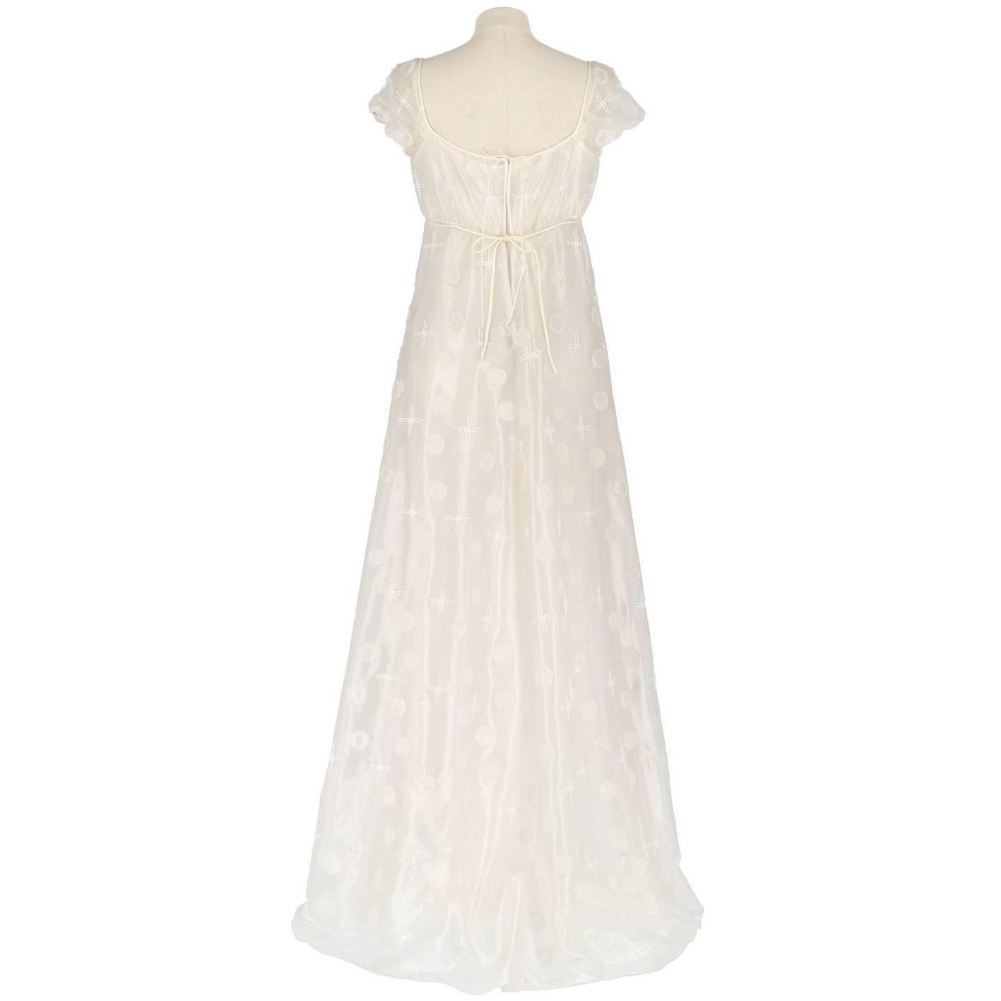 Marvelous Alberta Ferretti wedding dress decorated with white and transparent beads. The dress is hight waisted, with a white coulisse fastened on the back, and short sleeved, decorated with cross and rounds all over the dress, and includes the slip