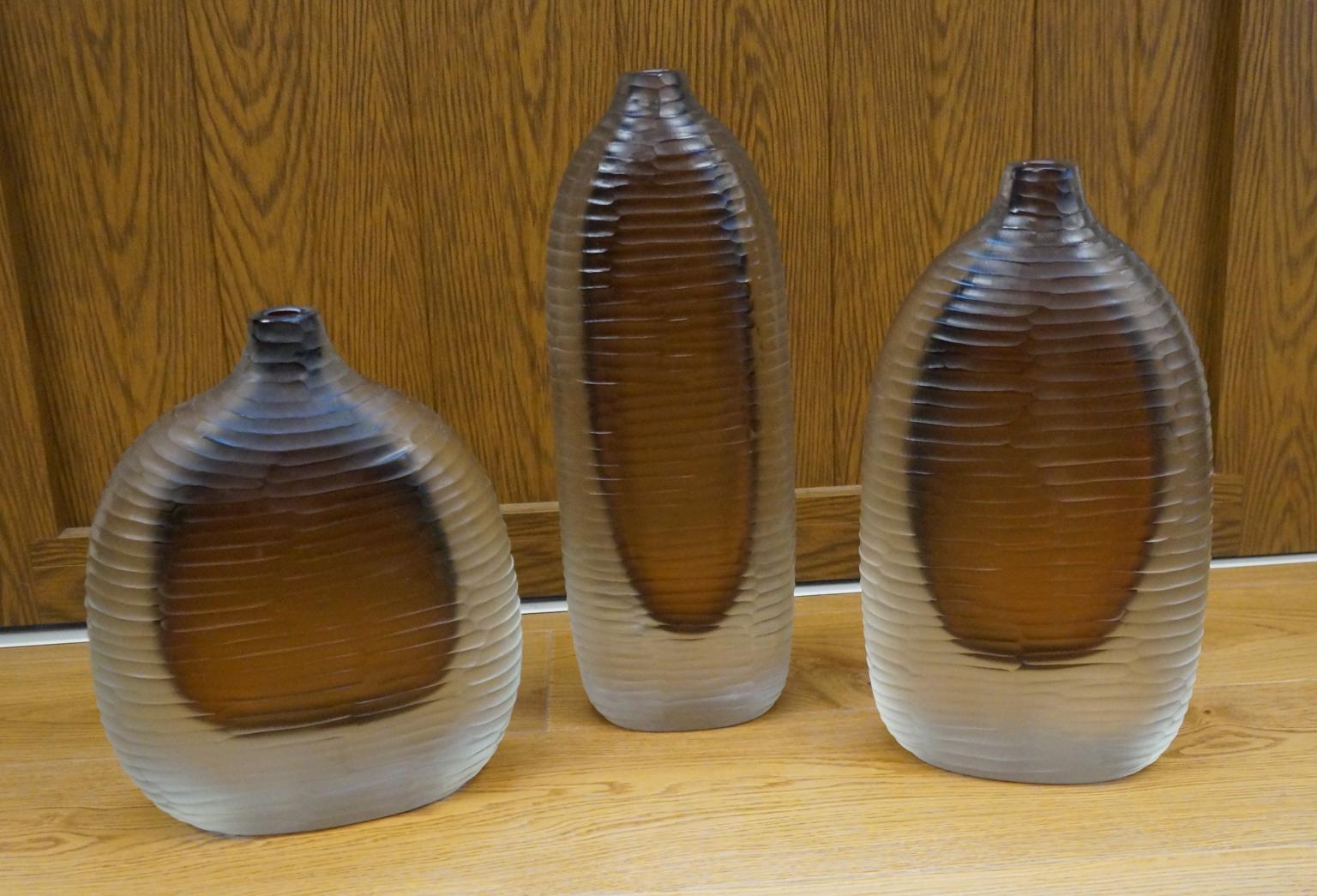 Drei Vasen aus mundgeblasenem Muranoglas Molato (graviert), Farbe klar und Bernstein innen.
Um diese Arbeit auszuführen, sind zwei verschiedene Prozesse erforderlich: Der erste besteht darin, die heiße Vase zu modellieren und ihr Form und Farbe zu