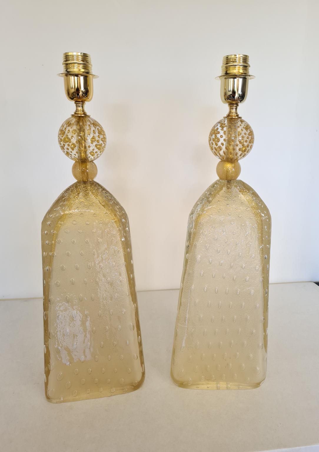 Exclusive pair of Murano glass table lamps in sandblasted gold crystal color.
The lamps have a process called Balloton that is submerged glass bubbles.
Triangular lamps with golden sphere.
The products are entirely handmade in the Mid-Century