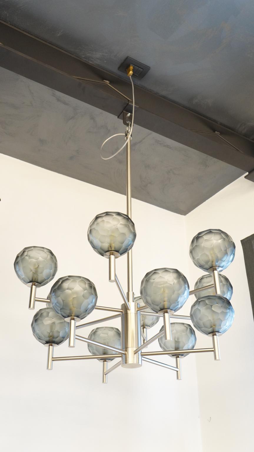 Kronleuchter aus Murano-Glas von Alberto Donà mit grauen, gravierten Glaselementen. 
Kronleuchter mit 12 Lichtern und satiniertem Silberrahmen. Ideal sowohl für ein modernes als auch für ein klassisches Umfeld.

Entworfen von Alberto Dona' im