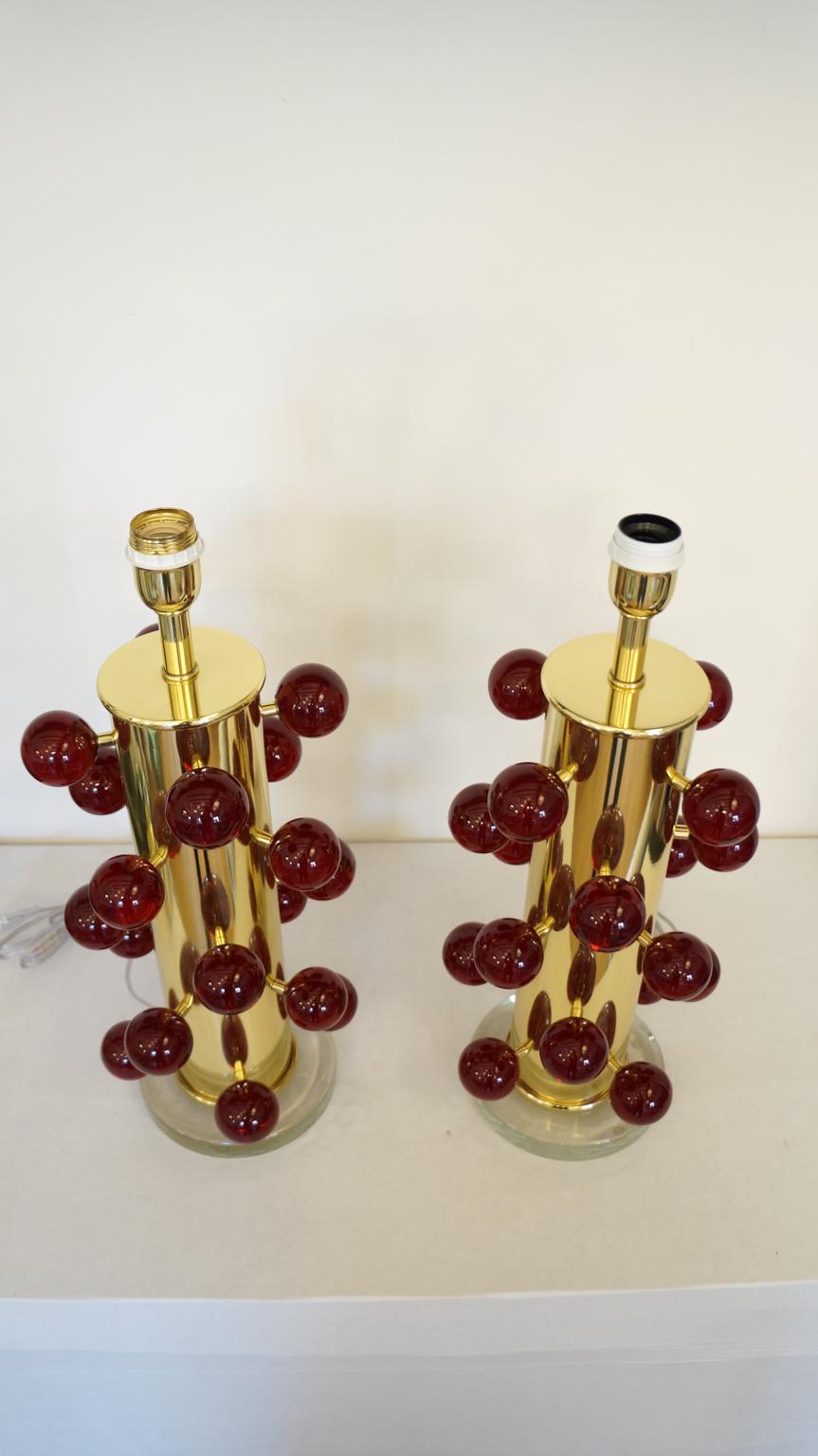 Exclusive pair of Murano glass table lamps with Pulegoso red spheres, transparent crystal base and gold chromed frame. 
Pulegoso processing are bubbles inside the color.
Lamp made with great care and precision by our master glassmaker Alberto Donà