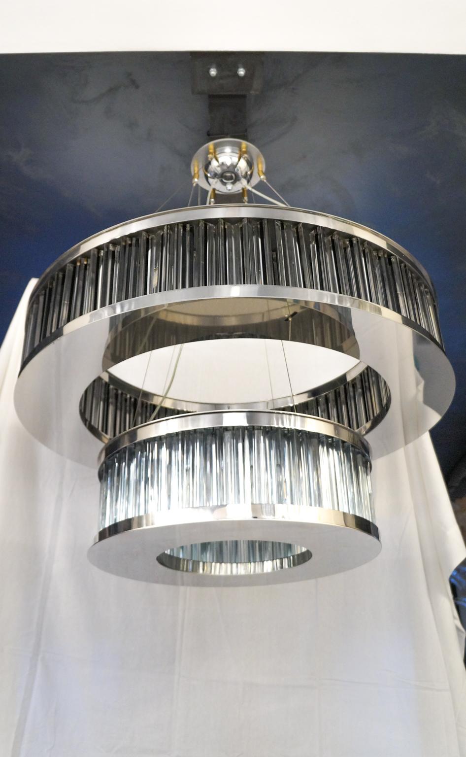 Certainly an effigy chandelier, which is structured in two metal rings vaguely reminiscent of the satellites of the planet Saturn. The first ring, the largest, is made up of 150 tryedral glass elements, while the second ring is made up of 84