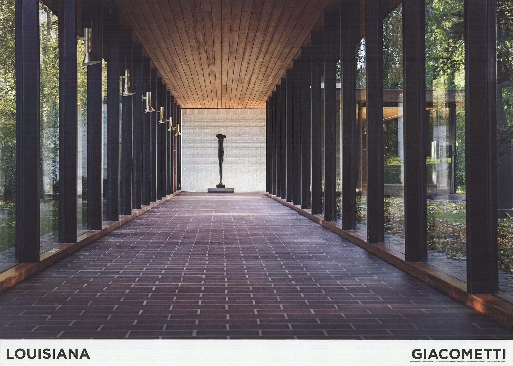 This museum poster, created for the Louisiana Museum of Modern Art, captures Femme Qui Marche I, one of Alberto Giacometti’s most iconic sculptures, positioned at the end of a hallway with a large window behind it. The placement allows natural light