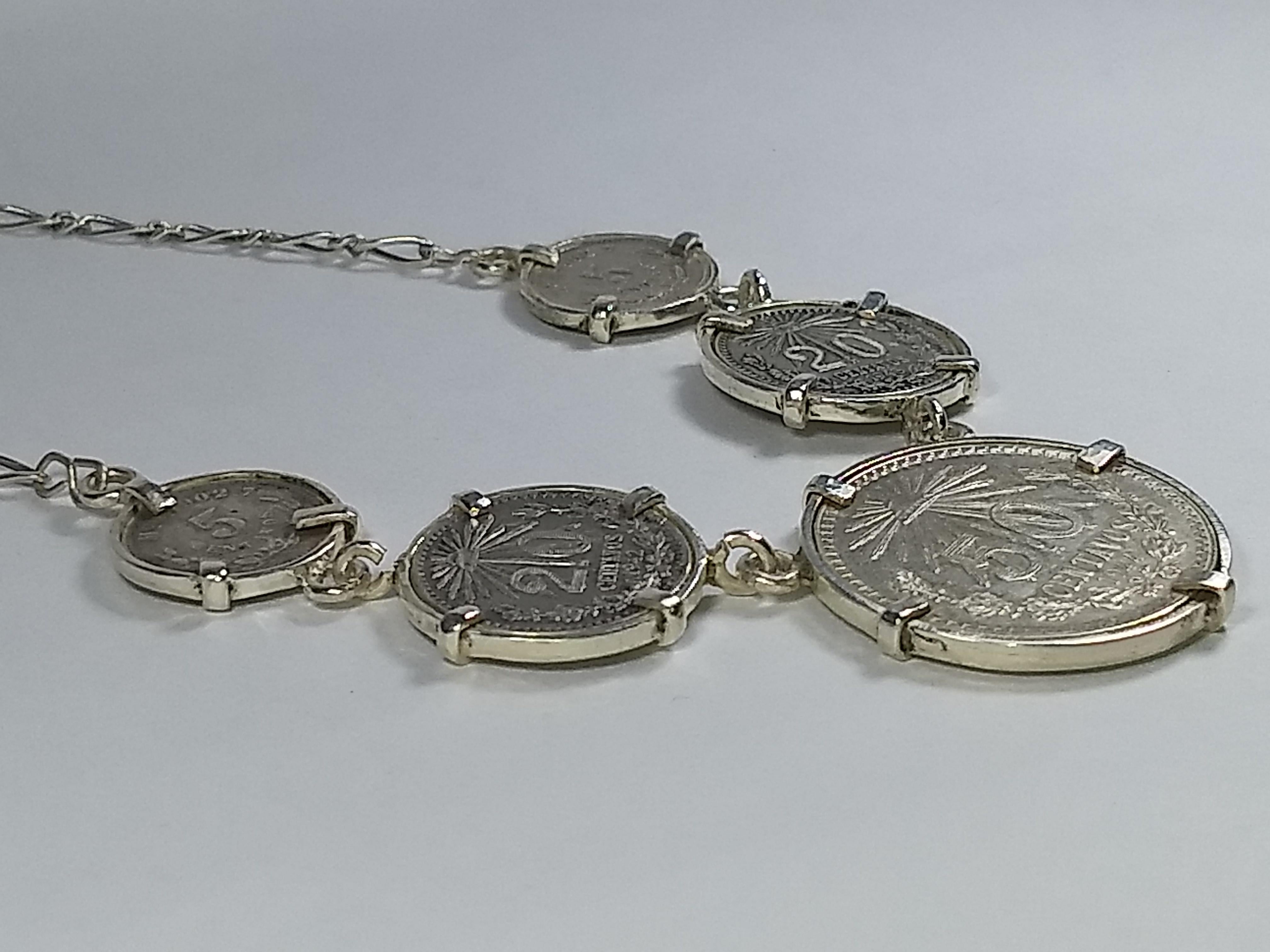 This Alberto Juan one of a kind necklace was handmade from Mexican silver coins with one 50 cent coin, two 20 cent coins, and two 5 cent coins of silver .720.,  The chain and findings used in this piece are sterling silver. Necklace measures 17