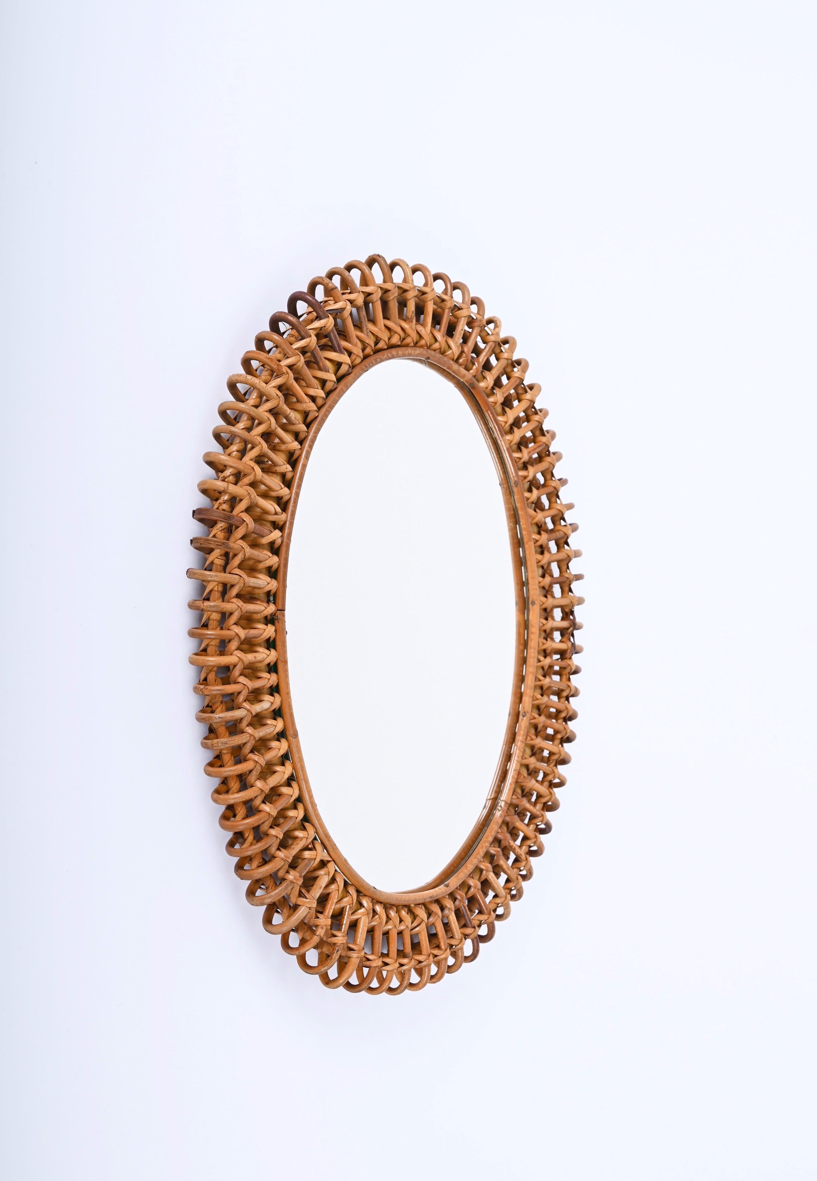 Fantastic Cote d'Azur mid-century oval wall mirror in bamboo, rattan and wicker. This astonishing piece was produced in Italy during the 1960s, and it is attributed to the mastery of Franco Albini.

This wonderful mirror features a double frame in