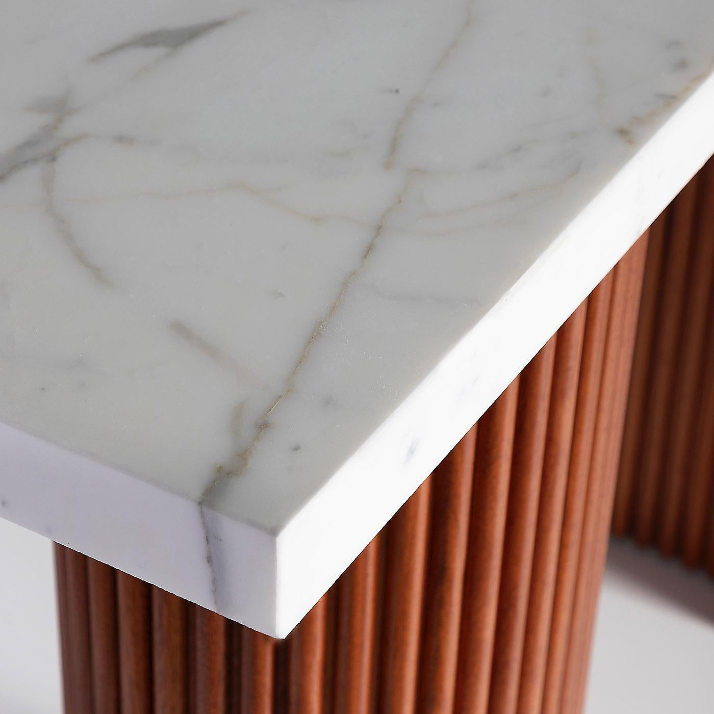 Part of the Alchimia Collection, this console boasts a sculptural silhouette sure to uplift any modern entryway or hallway. A thick rectangular top in prized Calacatta Oro marble rests on a couple of ribbed mahogany legs offering a new perspective