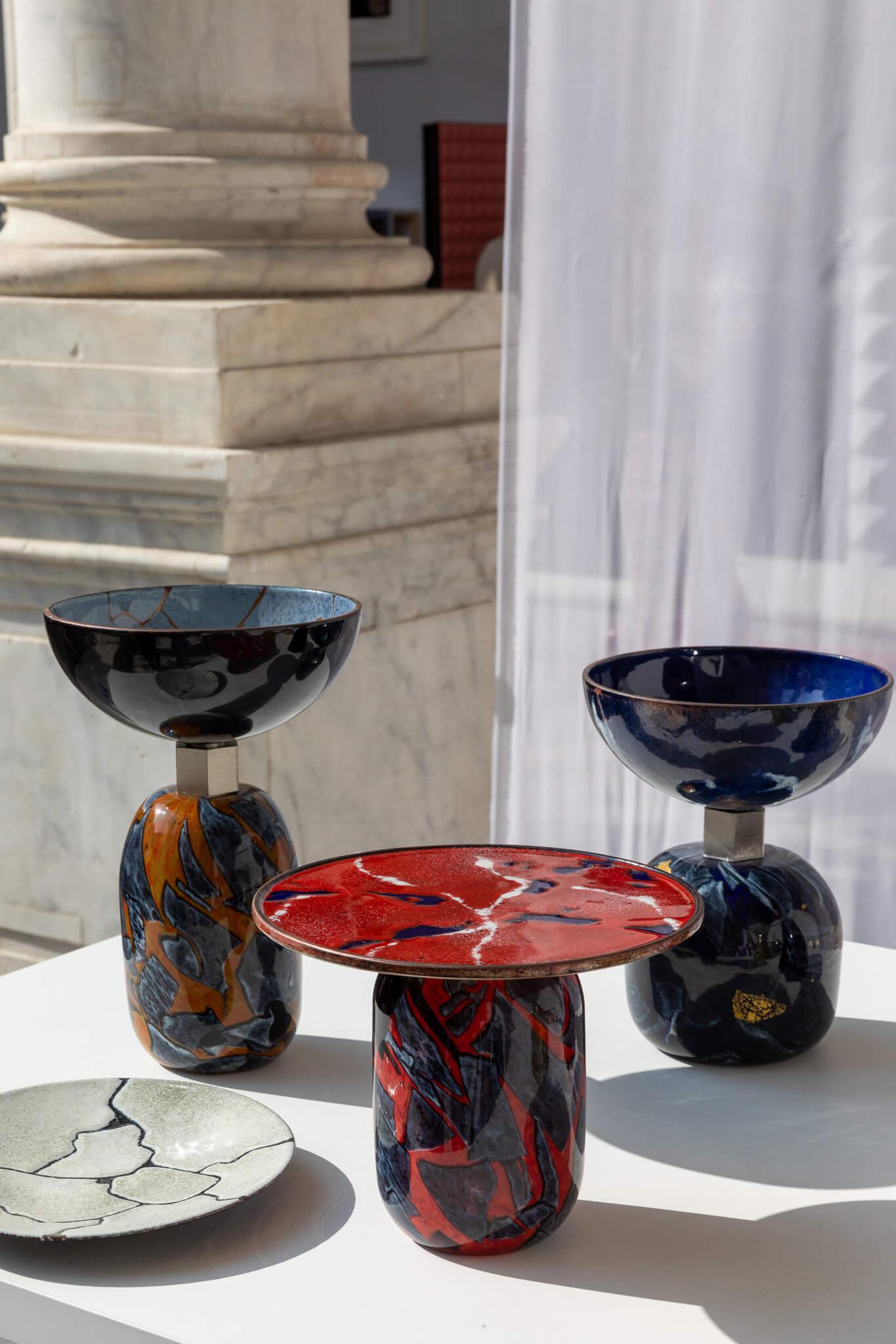 Alchimie, la capsule collection nata dalla collaborazione tra Incalmi e Debonademeo, riesce nel suo intento di trasformare la polvere di vetro in qualcosa di diverso. Vasi, vassoi e lampade evolvono il potenziale del vetro e del metallo di Murano,