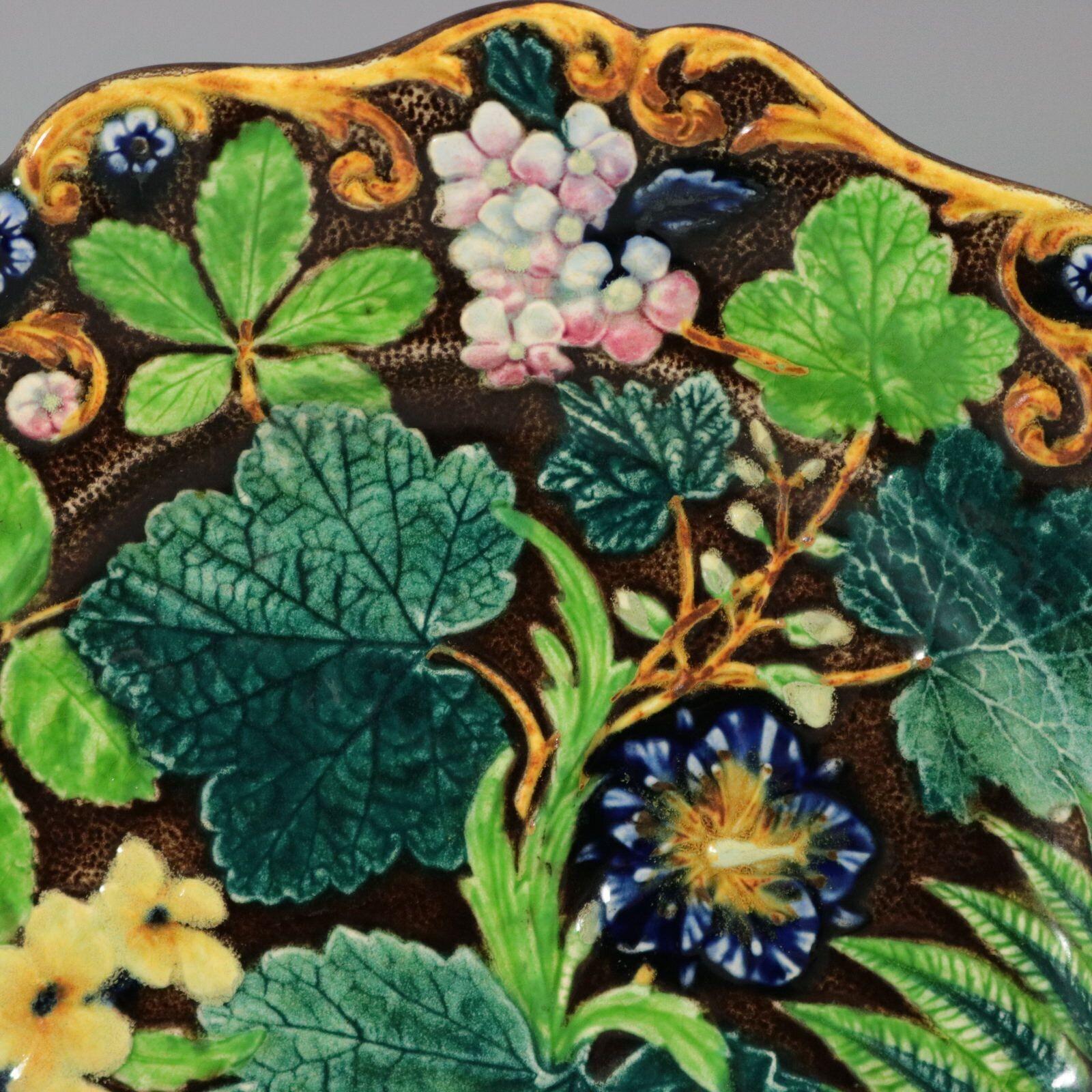 Alcock Majolica plate which features a stunning array of flowers and leaves. Colouration: brown, green, blue, are predominant.