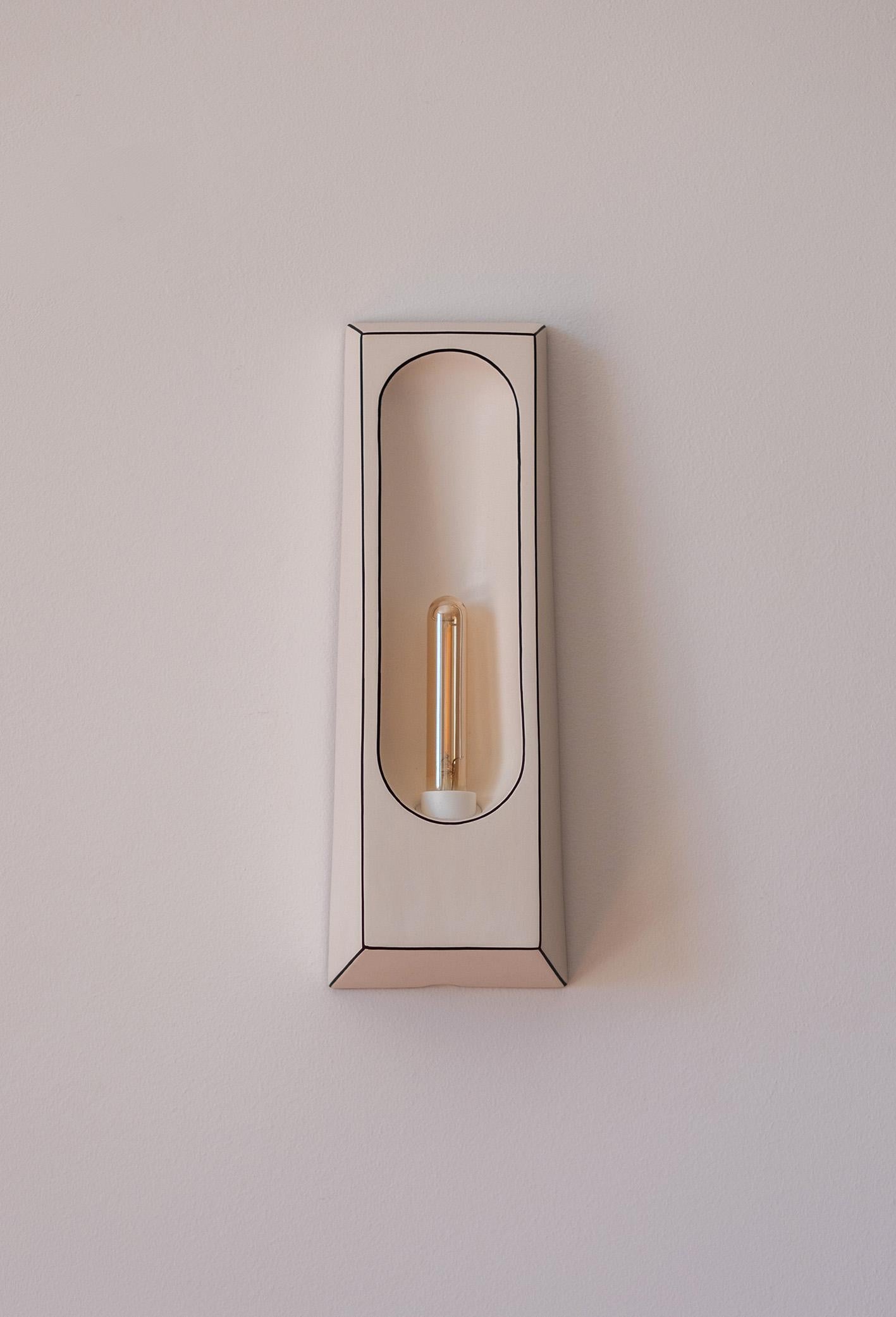 Lampada da parete Alcove Facette di Violaine d'Harcourt
Dimensioni: D 7 x L 12 x H 33 cm.
Materiali: Bisquit e inchiostro scuro.

Lampada da parete realizzata in Portogallo, lampadina inclusa: LED E14 1W non dimmerabile. Disponibile in diverse