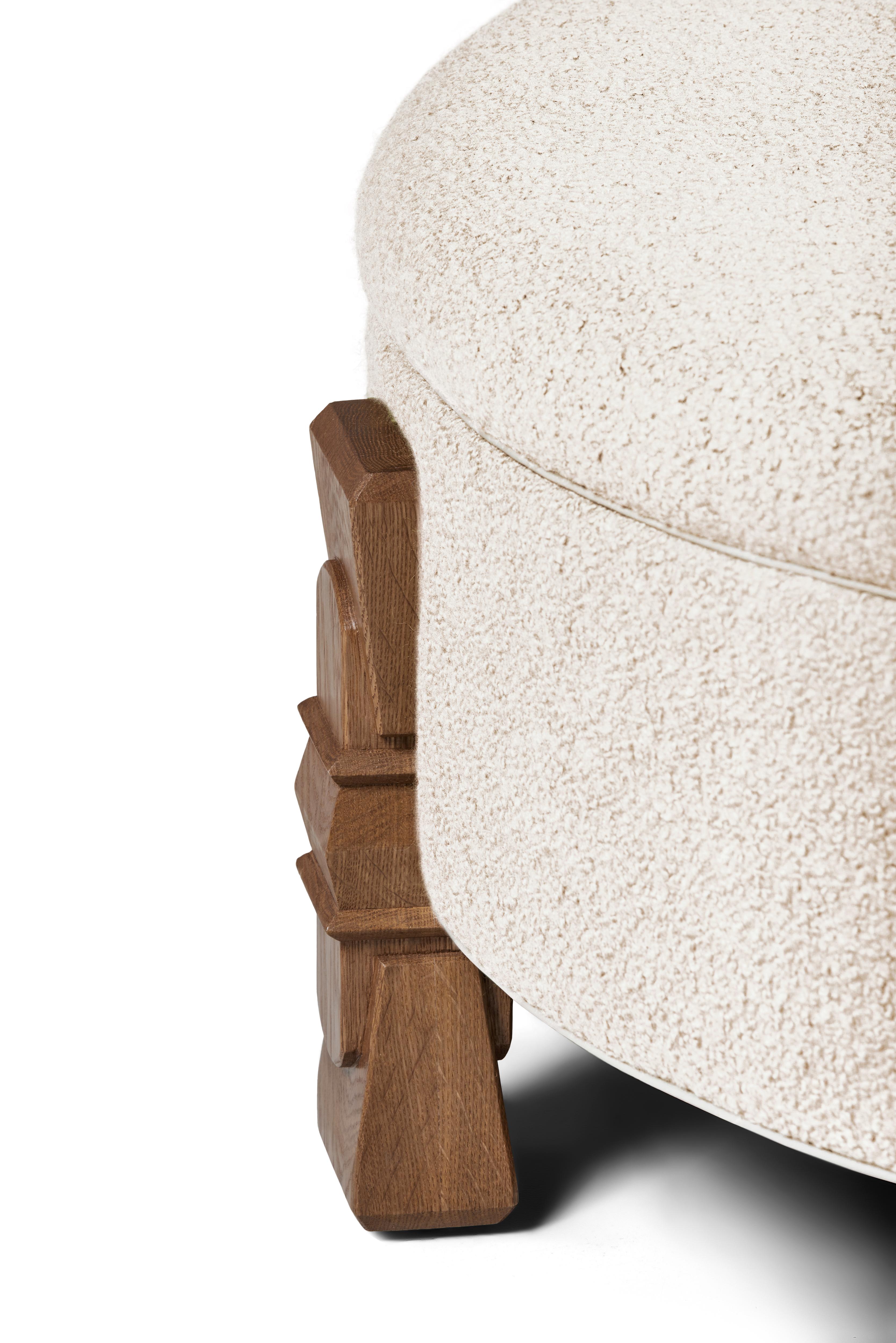 L'ottomana Alden, realizzata artigianalmente, è l'ultima novità della nostra linea. Un mix testuale di bouclé avorio e quercia bianca si combina con le bordature in pelle di questo pezzo unico. Le gambe intagliate a mano sono realizzate da artigiani