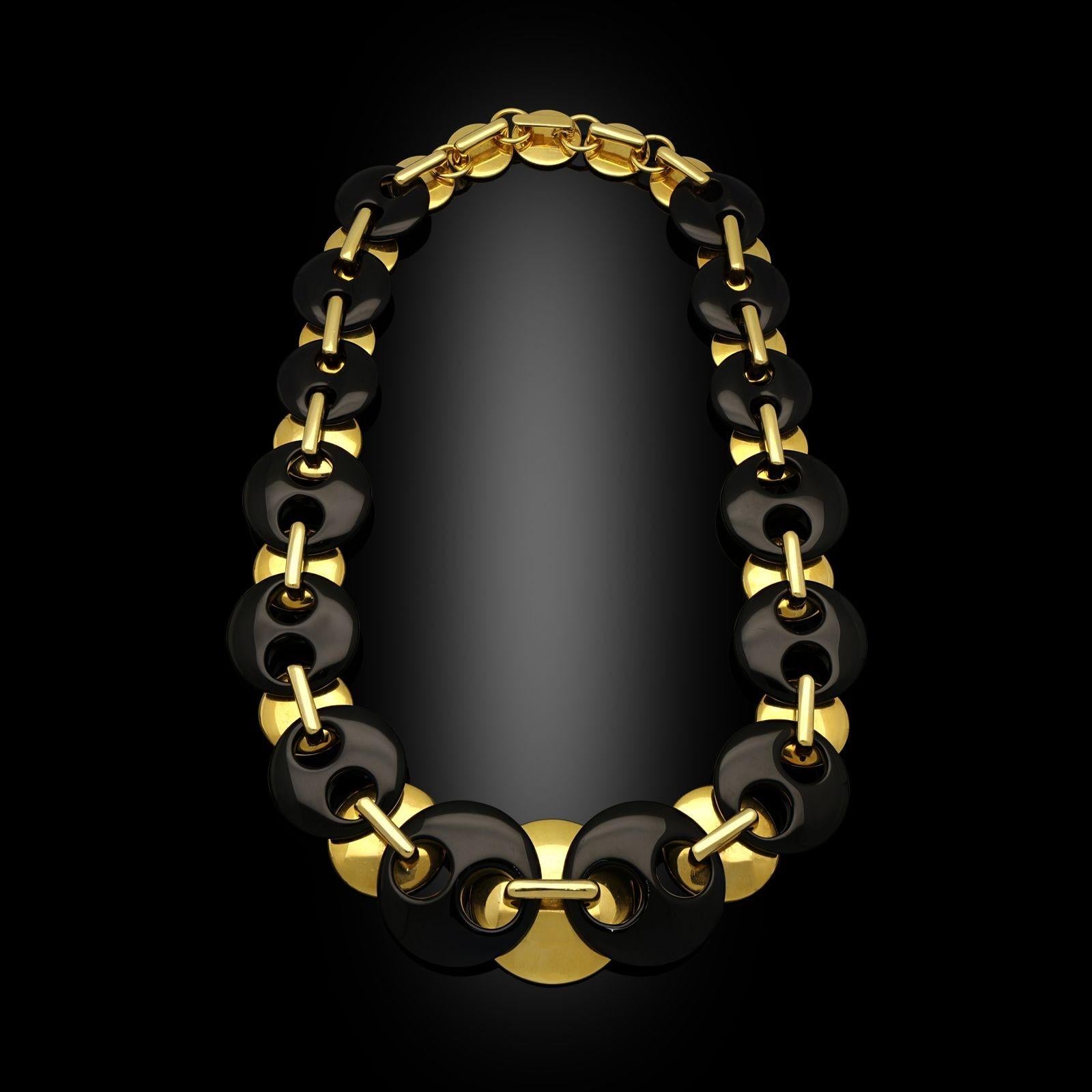 A wonderfully chunky and bold vintage necklace by Aldo Cipullo c. late 1970s, the necklace formed of eighteen circular domed discs of 18ct yellow gold, each with a rectangular geometric loop on top allowing it to be linked to the two carved and