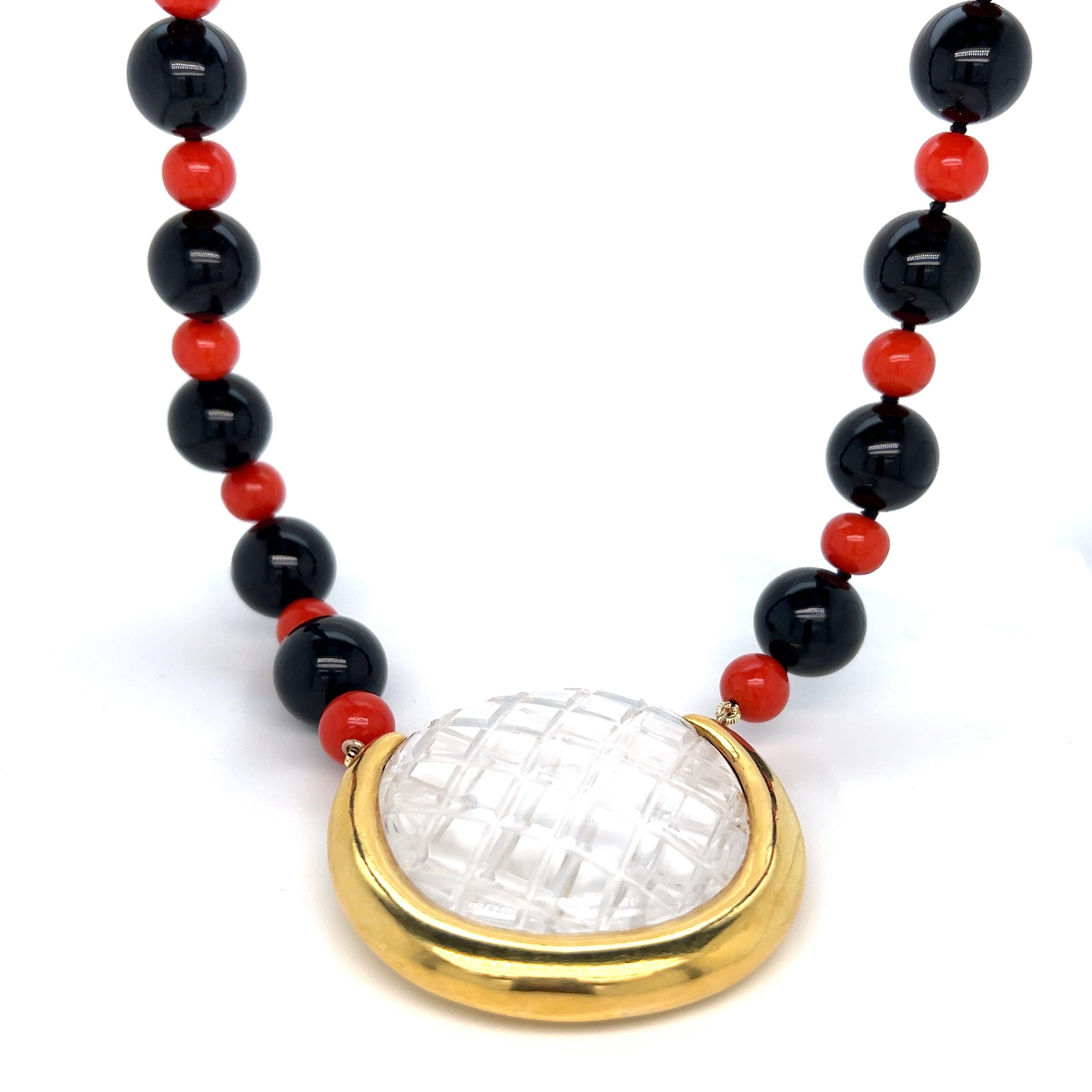 Aldo Cipullo 18 karat yellow gold crystal pendant beaded necklace. Its beads are made out of an extra long alternating black onyx (1.2 cm) and smaller corals (0.8 cm). The crystal features a criss cross pattern and is surrounded by gold on the sides