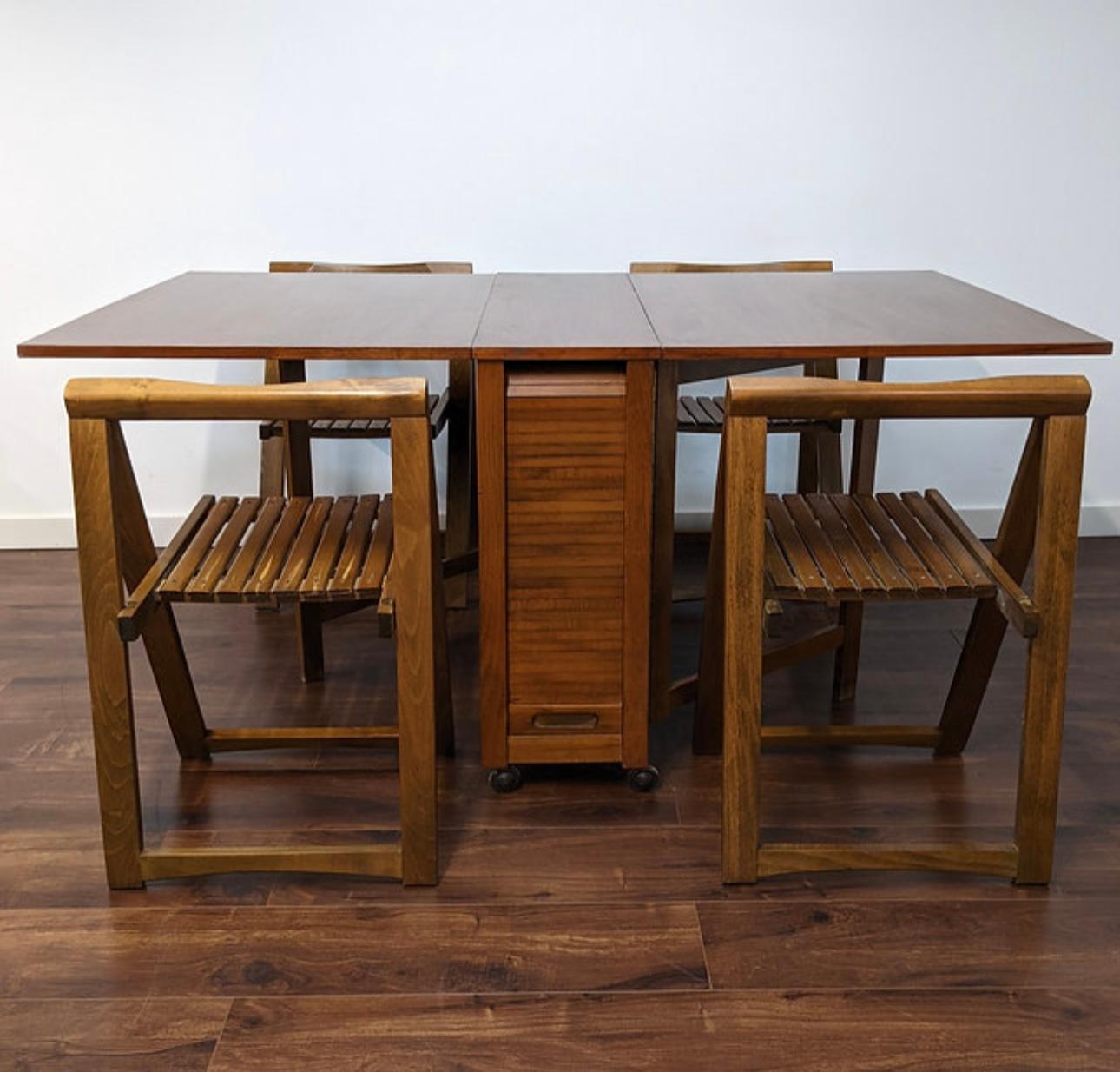 Classic Modernist dining table and 4 chairs for small apartments or extra holiday seating. The table has a charming Tambour door that reveals (4) slat seat folding chairs,
Great for an apartment or a vacation living, Danish style table has four