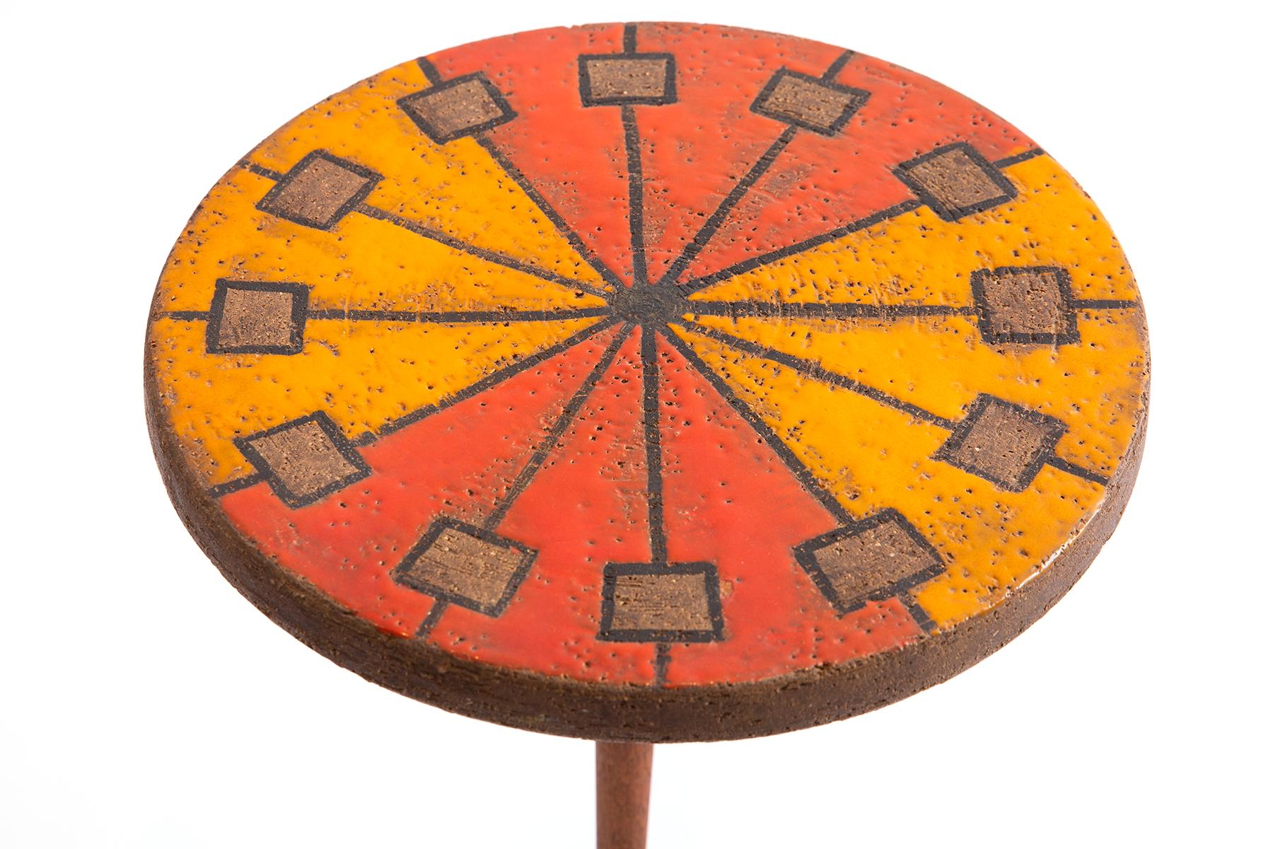 Aldo Londi for Bitossi ceramic iron and teak side table, circa late 1960s. This seldom seen example has a multi colored ceramic top with fluted teak stem and flared iron legs.