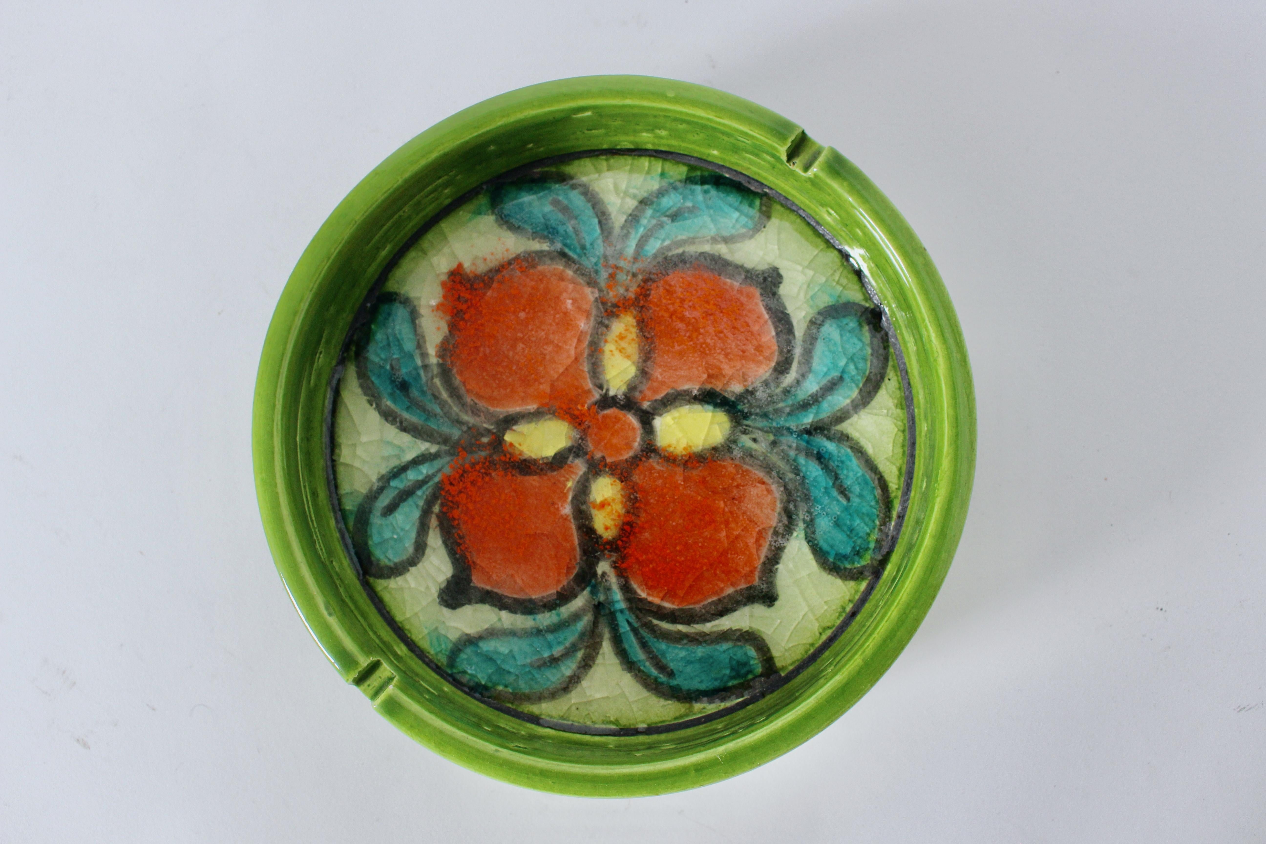 Cenicero Aldo Londi Bitossi esmaltado a mano de color Chartreuse con flores rojas. Cenicero de labios redondos con una flor roja delineada a mano con acentos turquesa y amarillo, reflejos rojos anaranjados rociados y esmalte craquelado brillante en