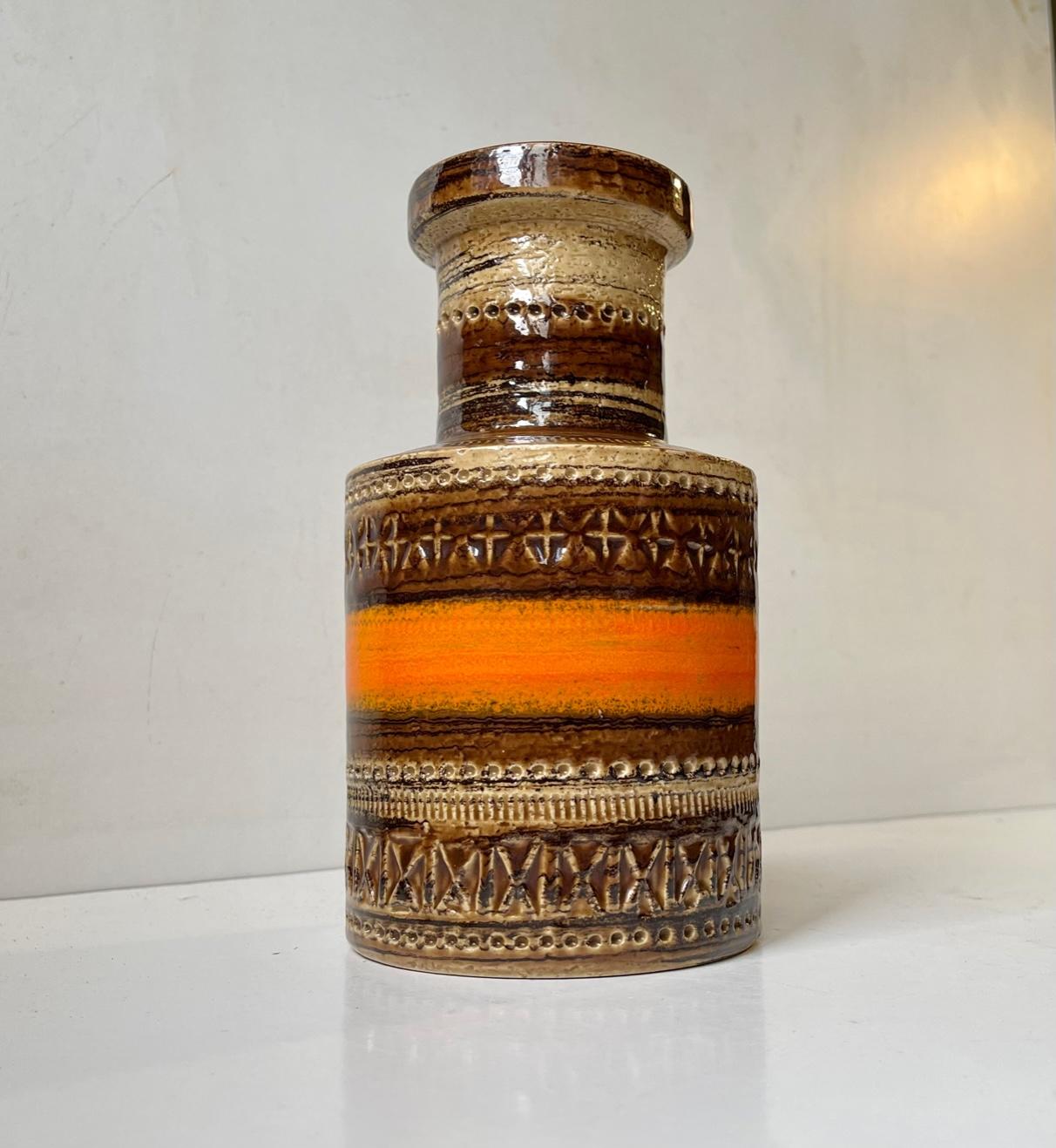 Aldo Londi designed this eye-catching stoneware vase. Its distinct decor is called Sahara and is executed in earthy, brown and vibrant orange glazes upon geometric patterns/symbols. It was manufactured in Italy by Bitossi for Raymor during the