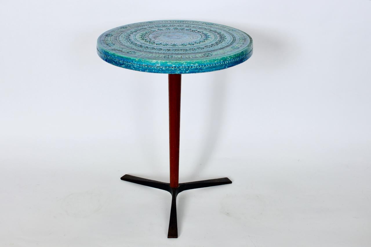 Aldo Londi for Bitossi incised blue and green Tripod Side Table distributed by Raymor Featuring a handcrafted  imprinted lipped circular glazed ceramic surface with incised decorative accents, in varied Green and Blue tones, atop a turned Walnut