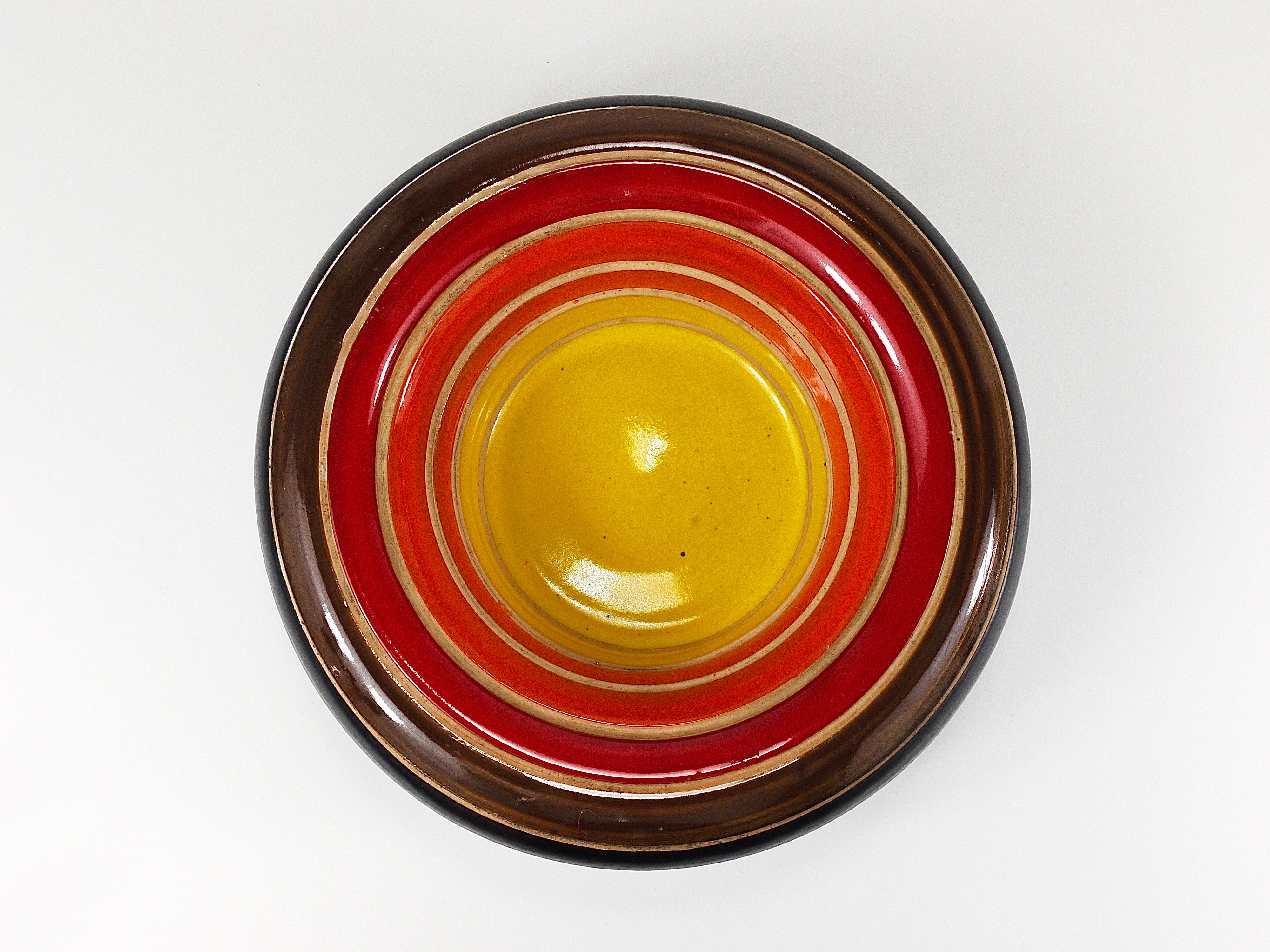 Un magnifique bol rond rayé en terre cuite, conçu par Aldo Londi, fabriqué à la main en céramique par le fabricant italien Bitossi Ceramiche dans les années 1960. Le bol présente six bandes horizontales, brillamment émaillées en jaune, orange,