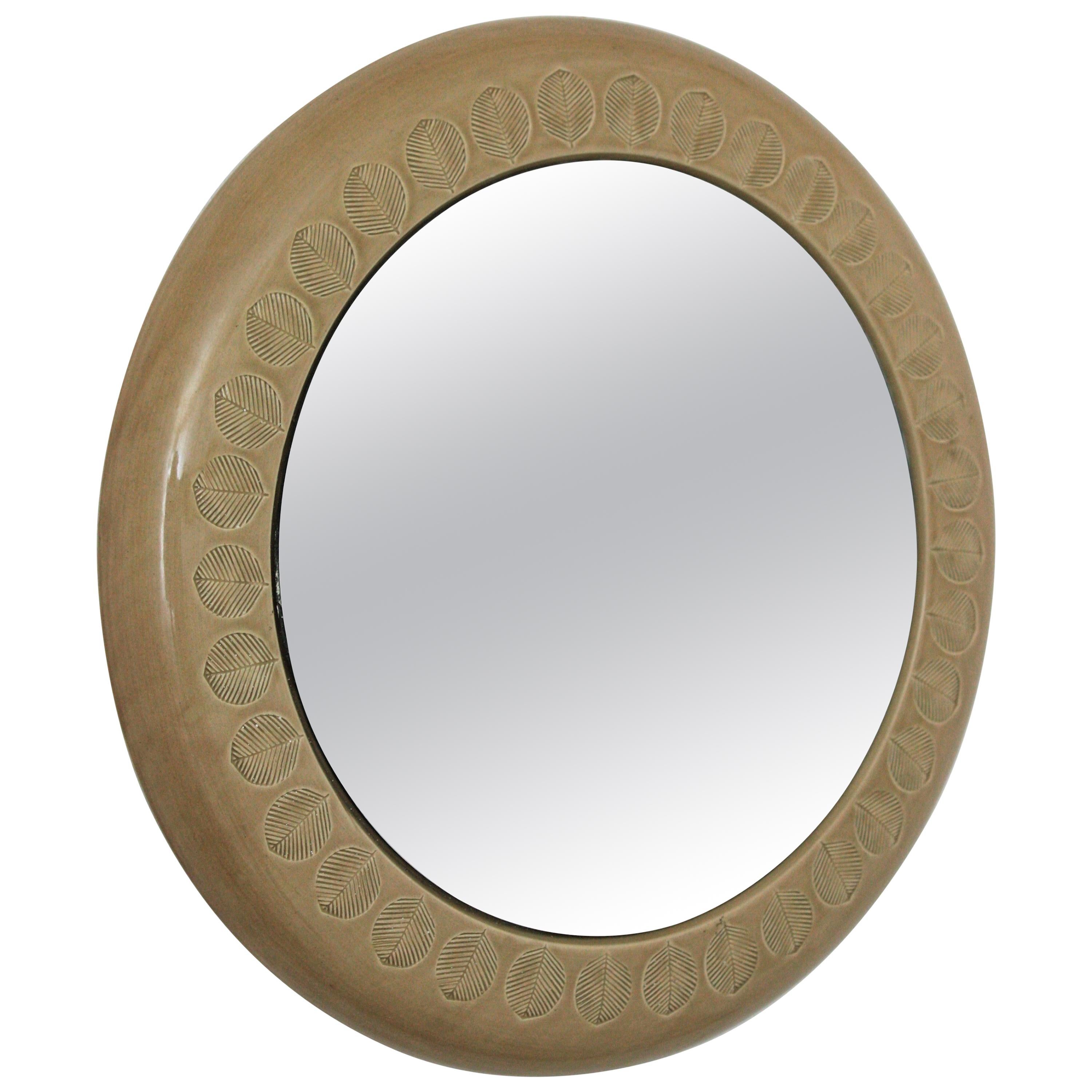 Round wall mirror by Aldo Londi for Bitossi, beige glazed ceramic and leaf motifs, Italy, 1960s.
Italian Mid-Century Modernist handcrafted beige-taupe terracotta glazed ceramic circular mirror with leaf pattern design.
Aldo Londi is widely known