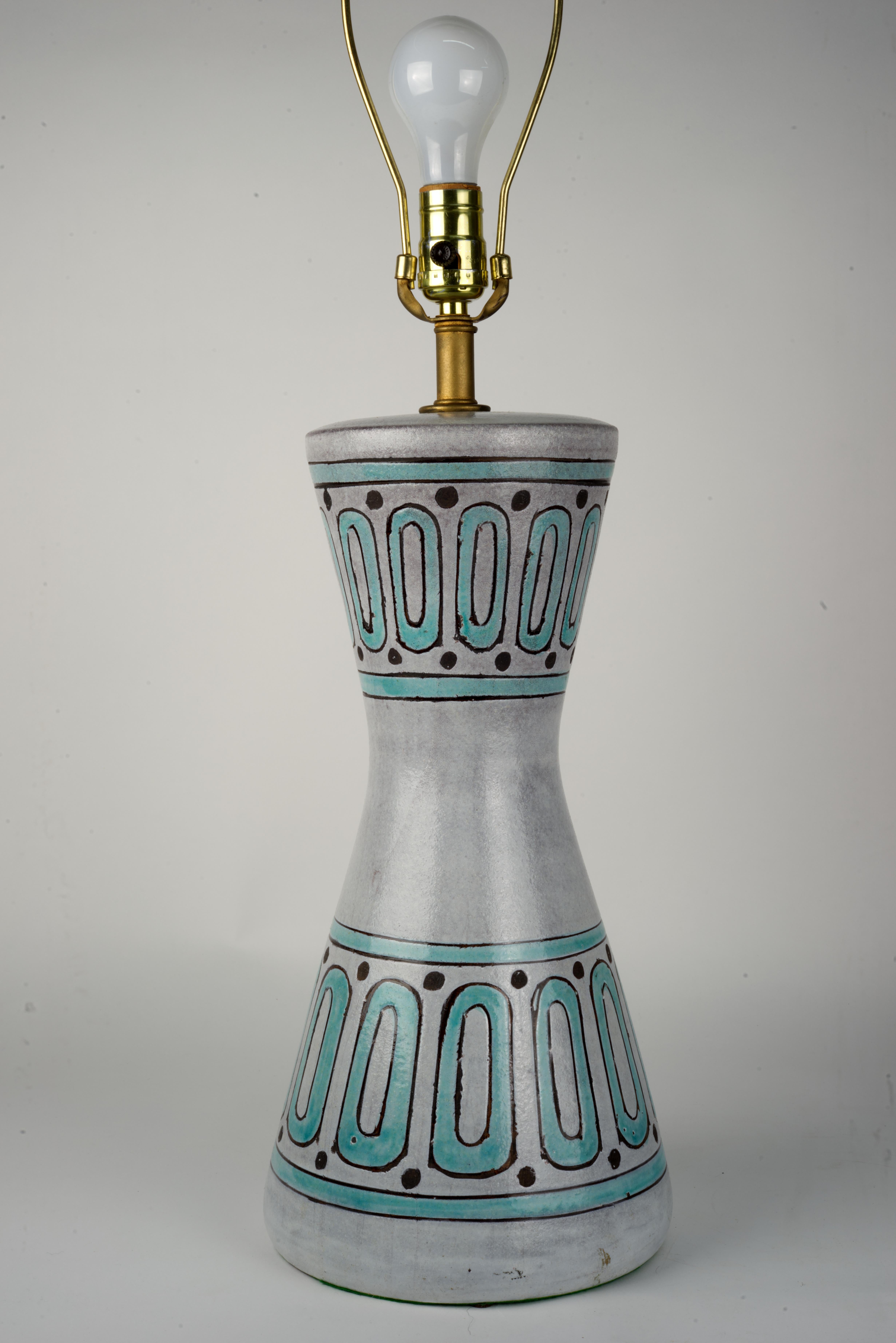 Rare and unusual Italian mid-century modern textured ceramic table lamp was designed by Aldo Londi for Bitossi Ceramiche. Hourglass-shaped lamp is decorated with two bands of incised abstract geometric decorations in teal and dark brown on pale
