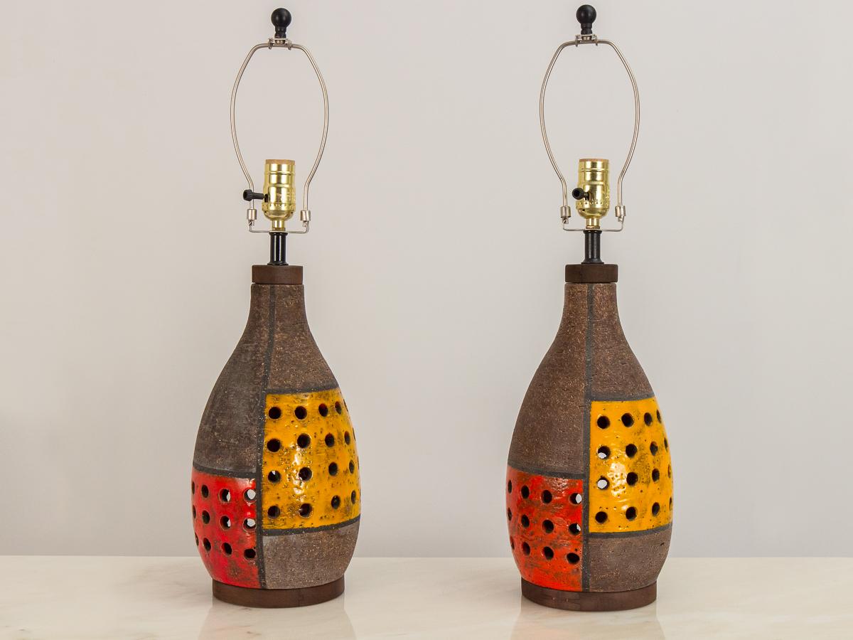 Pair of ceramic table lamps designed by Aldo Londi for Bitossi. Decorated in the bold Mondrian pattern, the minimal graphic motif is painted in a groovy palette of bright red and orange. Textured clay base is perforated. In good condition, with no