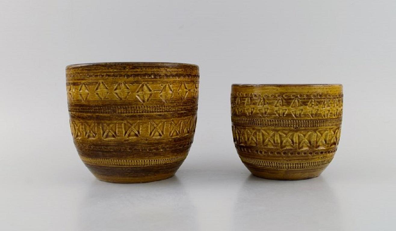Aldo Londi for Bitossi. Two flower pots in mustard yellow glazed ceramics with geometric patterns. 
1960s.
Largest measures: 15 x 12.5 cm.
In excellent condition.
Signed.
