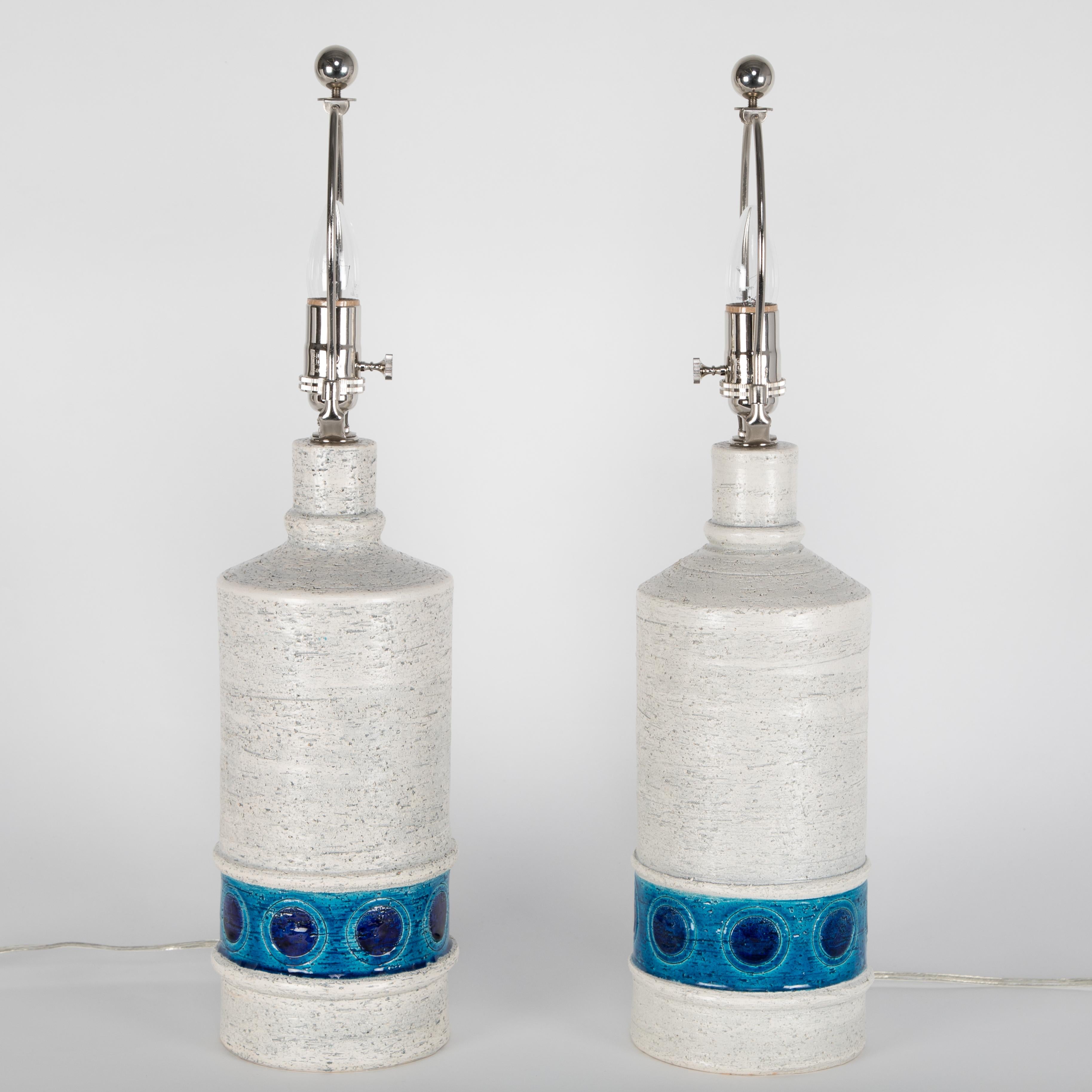 A fine pair of glazed ceramic table lamps in a textured, off-white color with a lower band of light and dark blues highlighting incised circular decorations. Designed by Aldo Londi for the collection 
