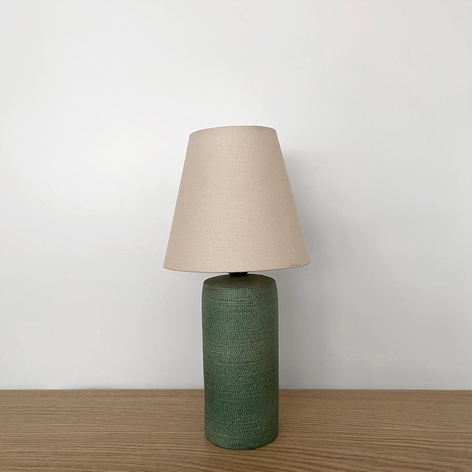 Manufactured by Bitossi
Organic composition and feel
Rich vibrant green ceramic lamp base is adorned with wonderful etched texturing throughout
New linen shade
Newly rewired
Single socket medium base with aged brass tulip shaped housing
Patina from