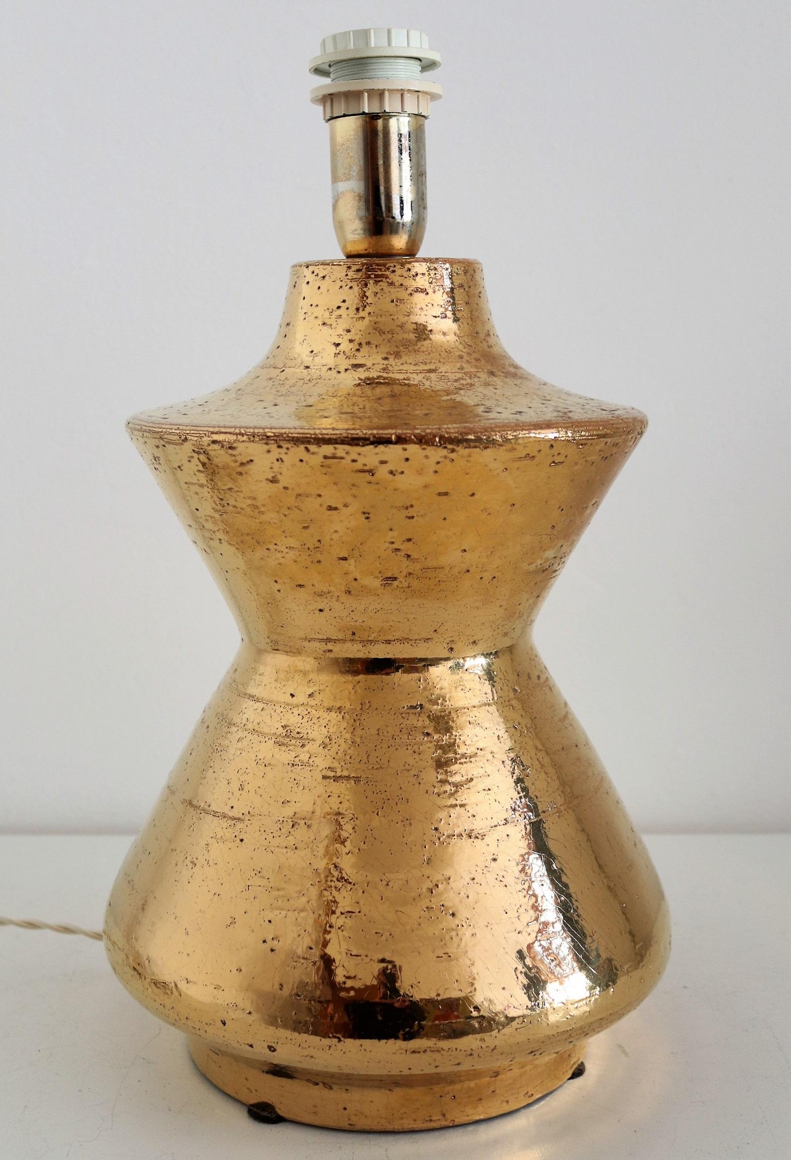 Beautiful and shiny ceramic table lamp designed and made under the artistic guidance from Aldo Londi in the 1970s for Bitossi.
This heavy, organic ceramic body is made in gold metallic glaze and a beautiful eye-catcher.
The lamp has been equipped