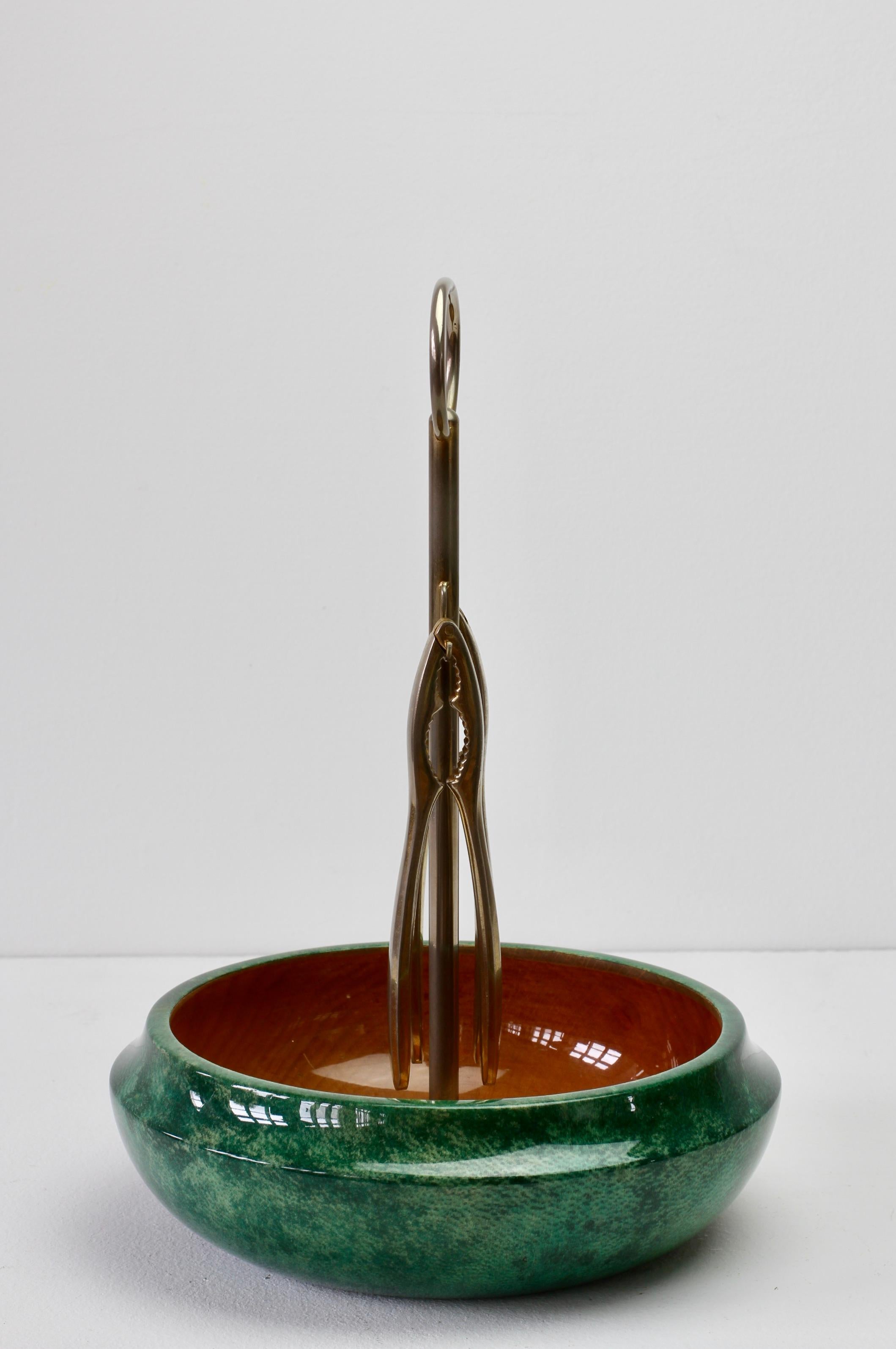 Midcentury Italian 1960s nut bowl with original nutcrackers by Aldo Tura, Milan. Signed with original label green colored and lacquered goatskin leather combined with cast metal carrier / holder is perfect for carrying your favorite nut selection to