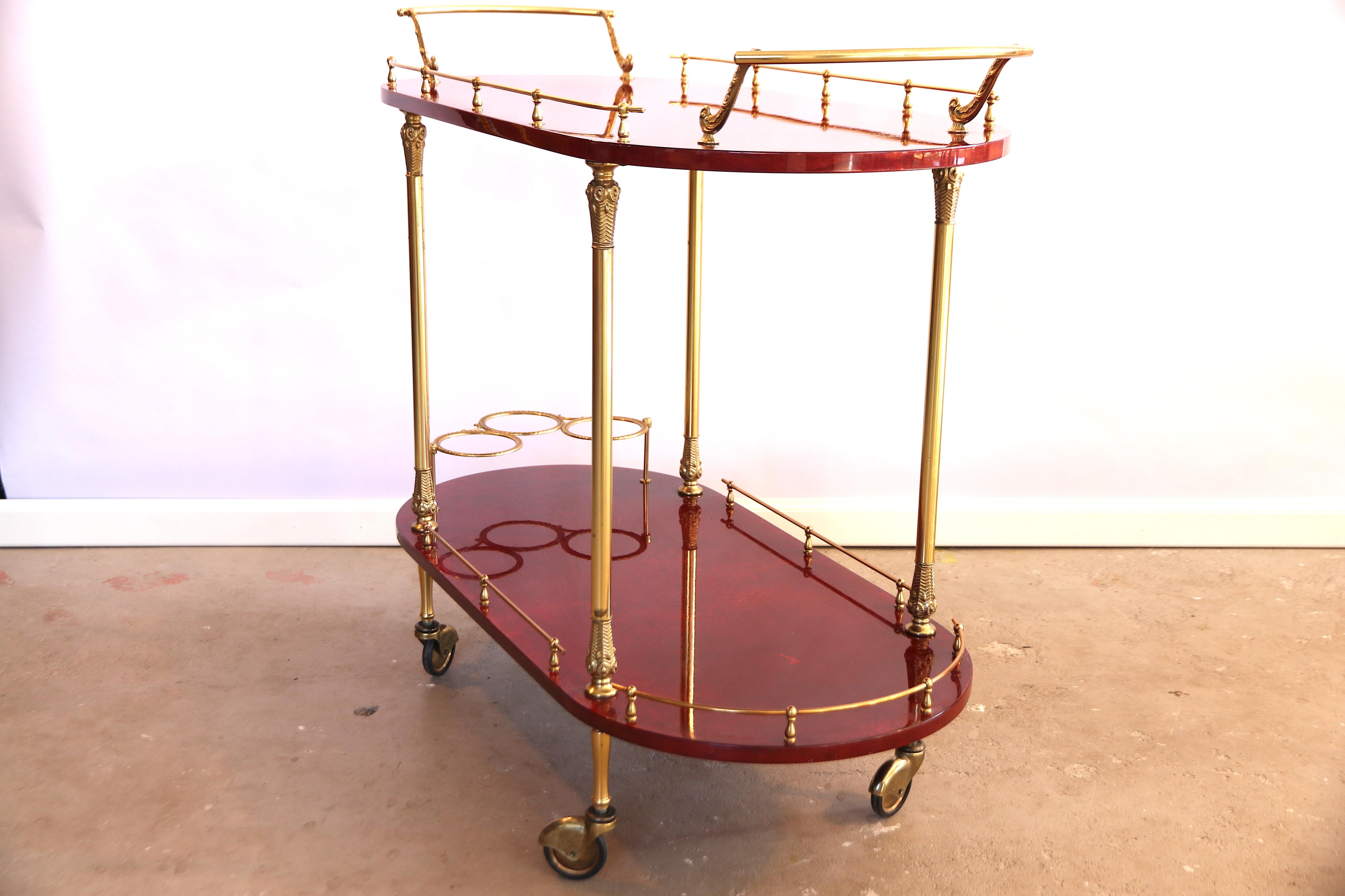 Absolutely amazing rare two-tiered red-dyed goat skin parchment with brass and copper bar cart, liquor trolley or tea trolley. This abundant piece has shiny brass hardware, high gloss lacquered red dyed goatskin parchment, copper casters and 3