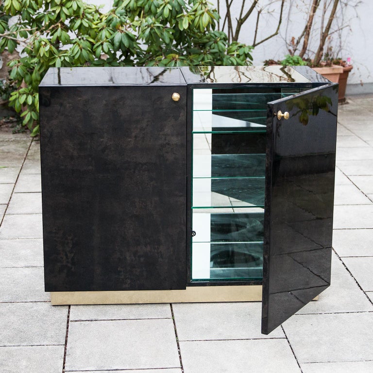 Elegant Aldo Tura parchment bar cabinet with brass details.
This beautiful small cabinet was mirrored inside with two glass shelves, and has a to open mirrored bar case on the top and an upper brass inset plate. All are in excellent original