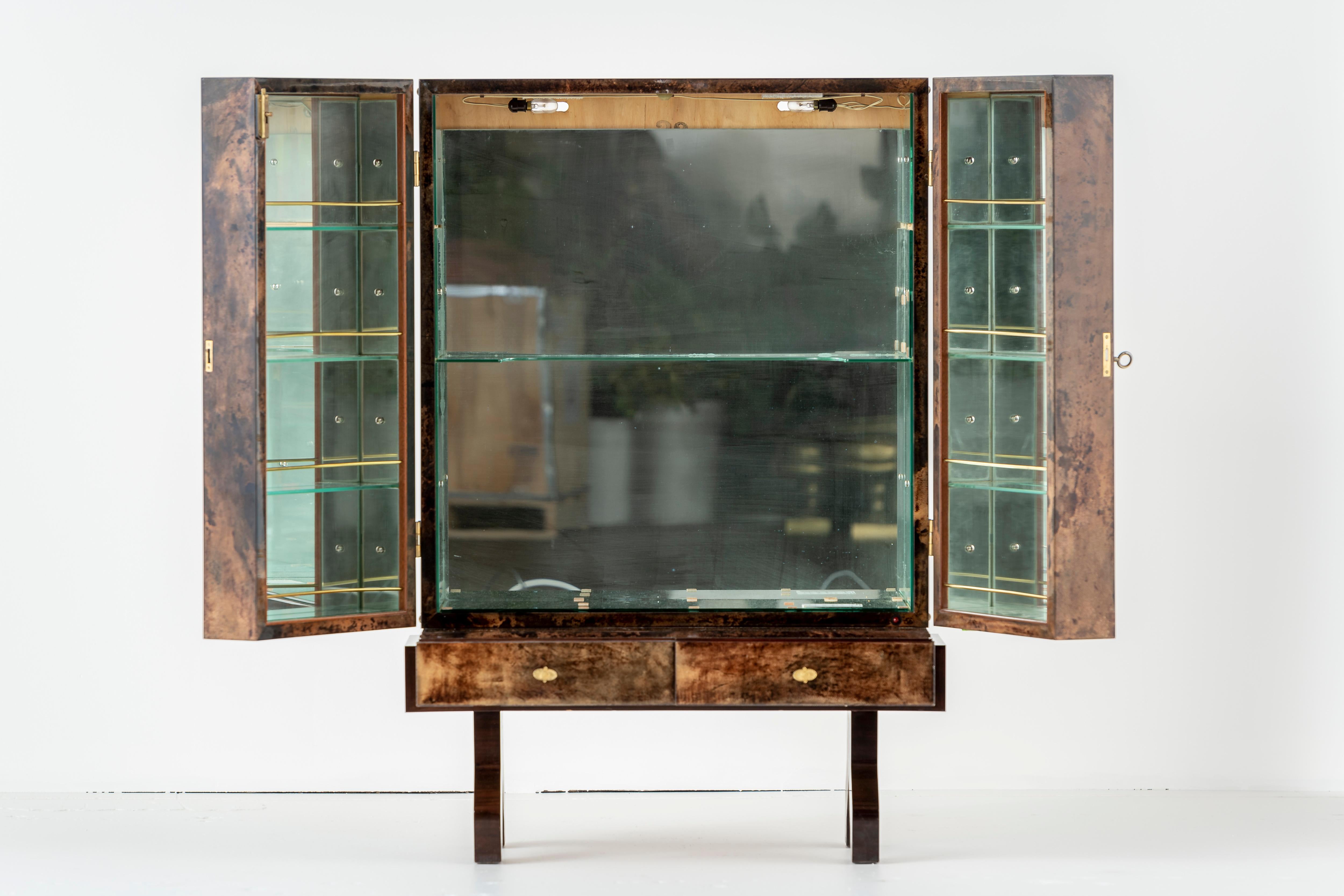 
Stunning bar cabinet in lacquered goatskin with gilded bronze hardware, by Aldo Tura. Mirrored and illuminated interior. Italy, mid-1960s. In good condition, few signs of wear. Four shelves on interior of each door. One interior shelf. Two drawers.
