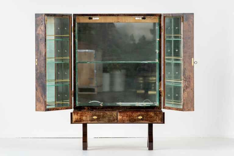 Bar cabinet in lacquered goatskin with gilded hardware, by Aldo Tura. Mirrored and illuminated interior. Italy, mid-1900s. In good condition, few signs of wear. Four shelves on interior of each door. One interior shelf. Two drawers.