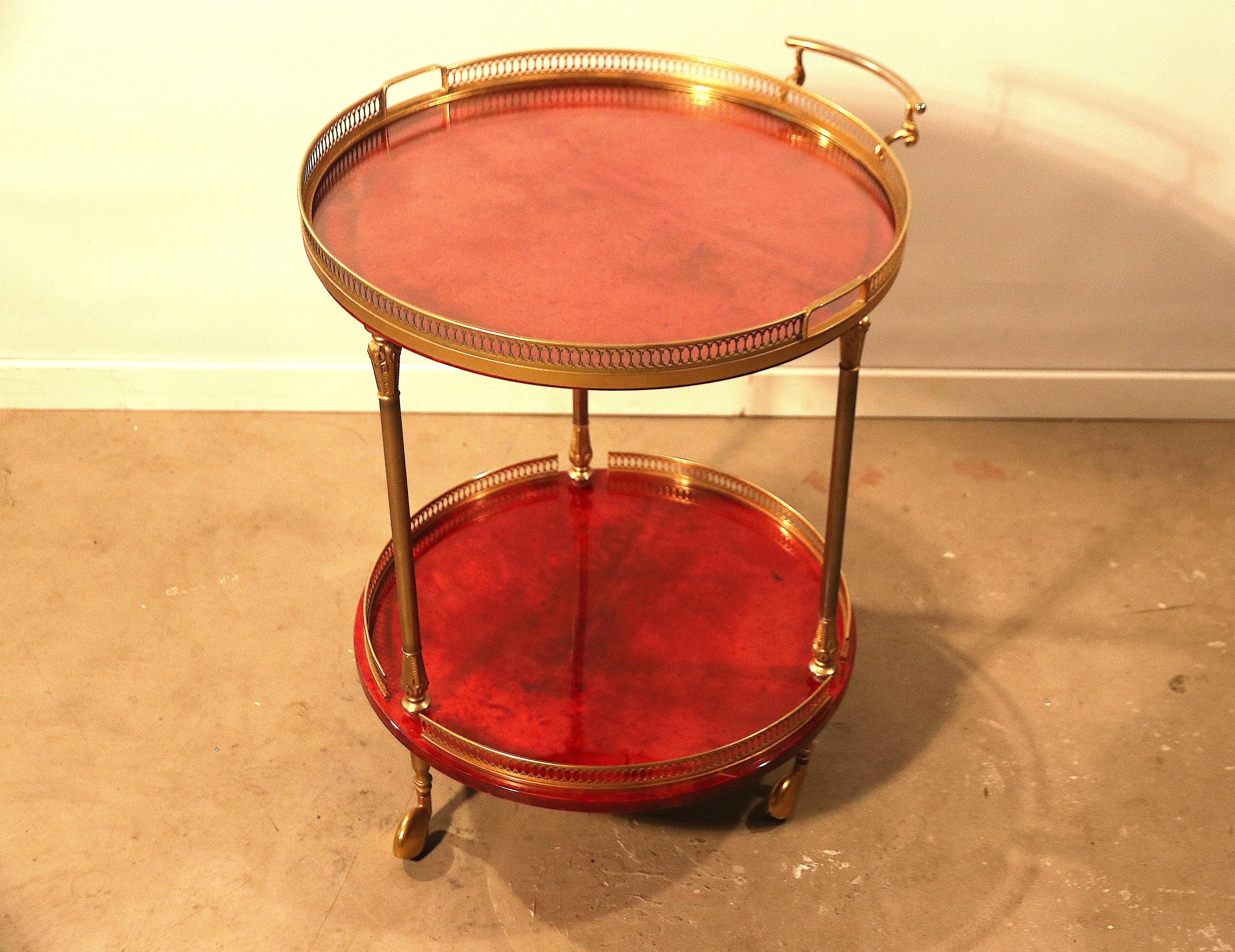 Astonishing piece designed and signed by Aldo Tura in vivid-red dyed goatskin leather or parchment. This is a 2-tier bar cart or tea / serving drinks trolley on 3 beautifully covered typically 1950s streamline brass casters. The top tray is a