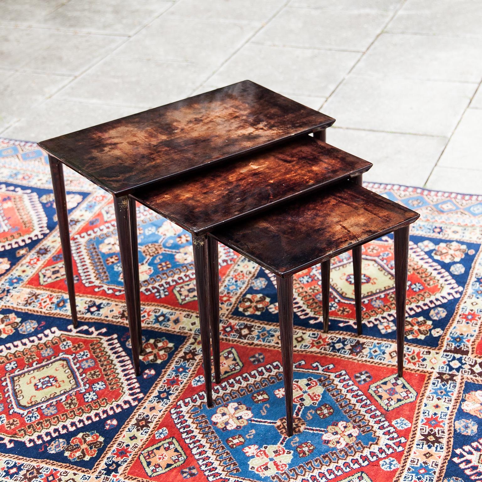 Nesting tables made by Aldo Tura in brown lacquered goatskin and executed circa 1970s with mahogany tained beech wood legs, in excellent condition. The price includes the set of three.
Along with artists like Piero Fornasetti and Carlo Bugatti, Aldo