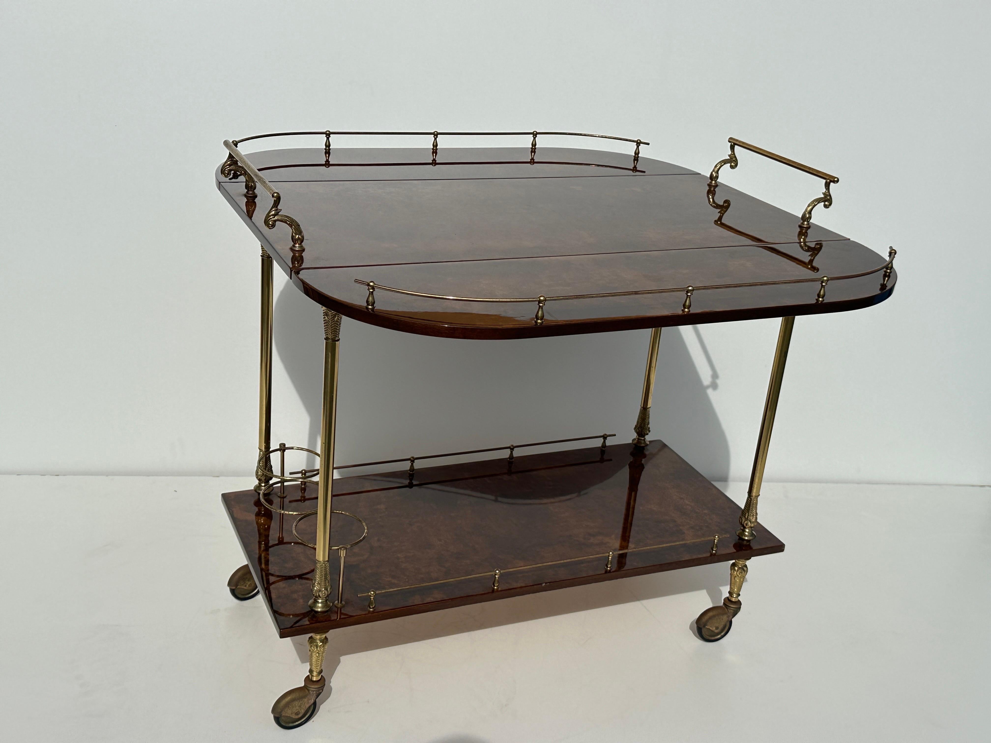 Chariot de bar italien à feuilles tombantes Aldo Tura en parchemin marron laqué.
Les roulettes en laiton présentent une certaine patine et un certain ternissement. Un pli sur le coin de l'étagère inférieure. Une bosse sur le coin supérieur de