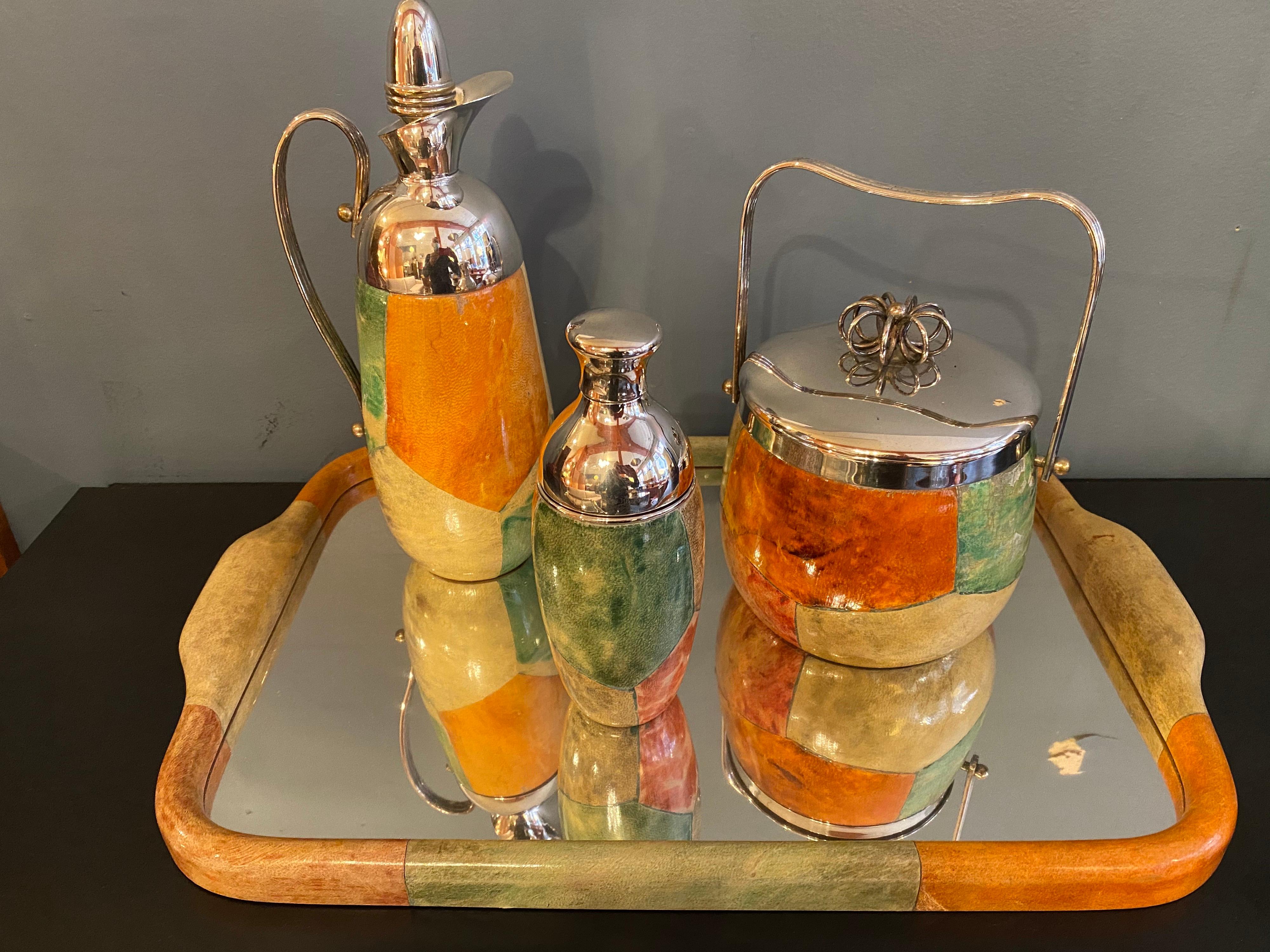Aldo Tura goat skinned drink set. Mirrored tray with matching tri-colored complimentary ice bucket, cocktail shaker and thermos carrafe. All in very nice condition, small splits in silver-plate cap on shaker. Goat-skin colors of orange, green and
