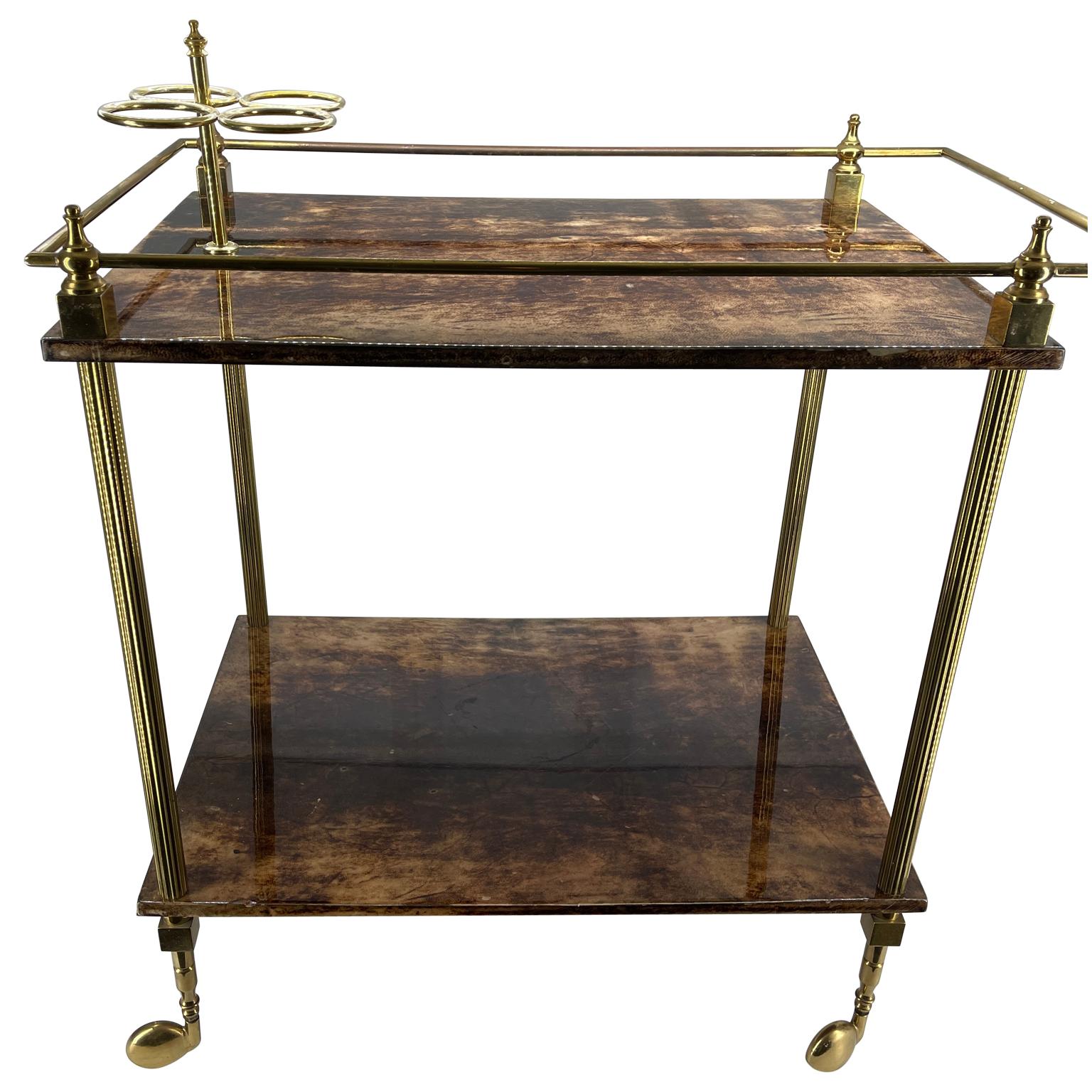 Mid-Century Modern Aldo Tura Goatskin and polished brass bar cart. A goatskin covered double tiered rolling bar cart with brass wheels, brass rails, handles and three ring bottle holder. The top tier of the bart cart displays a three bottle holder